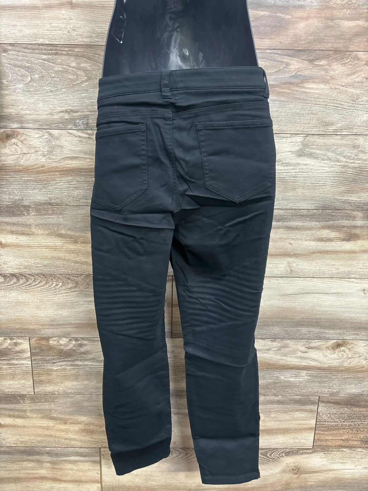 Back view of black Isabel maternity utility jeggings with over-belly panel, back patch pockets, slim legs on wood floor