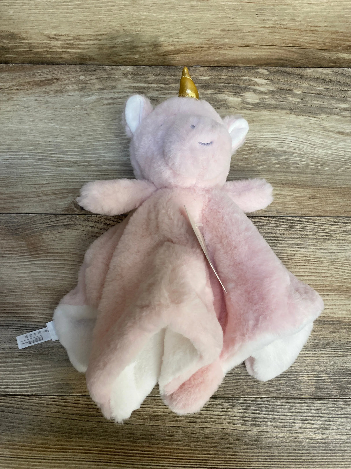 Pink unicorn plush security blanket for babies and kids on wood background