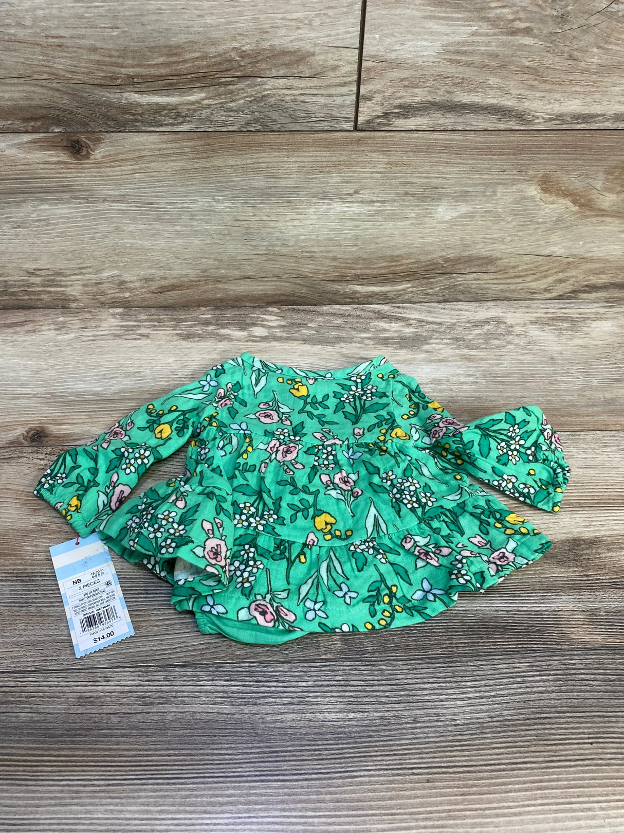 Flat lay of Cat and Jack newborn floral henley dress with bloomers showing ruffled tiers and long sleeves on wood background
