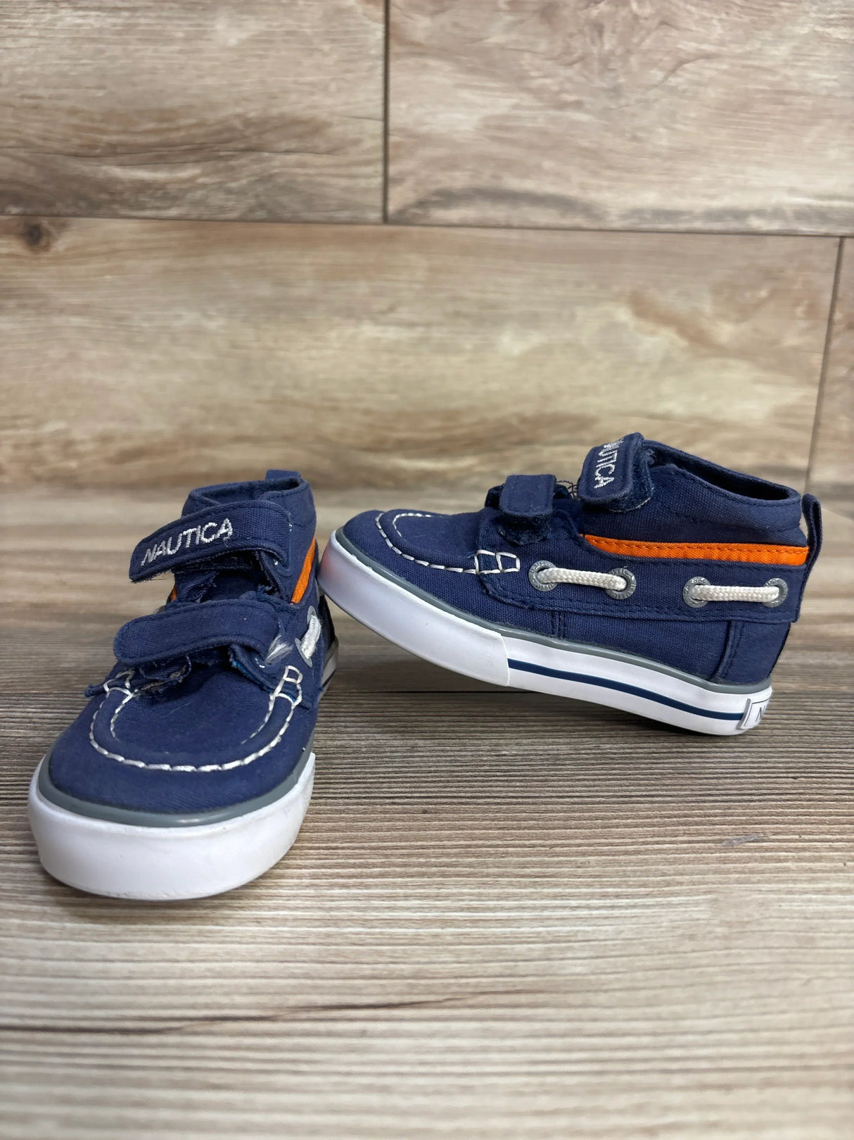 Nautica toddler navy sneakers with orange accents on wooden floor