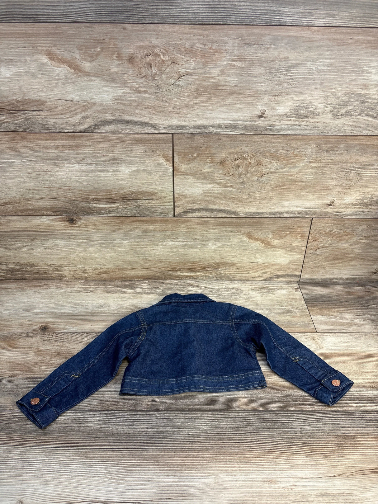 Kids dark blue denim jacket with long sleeves on wood background, back view