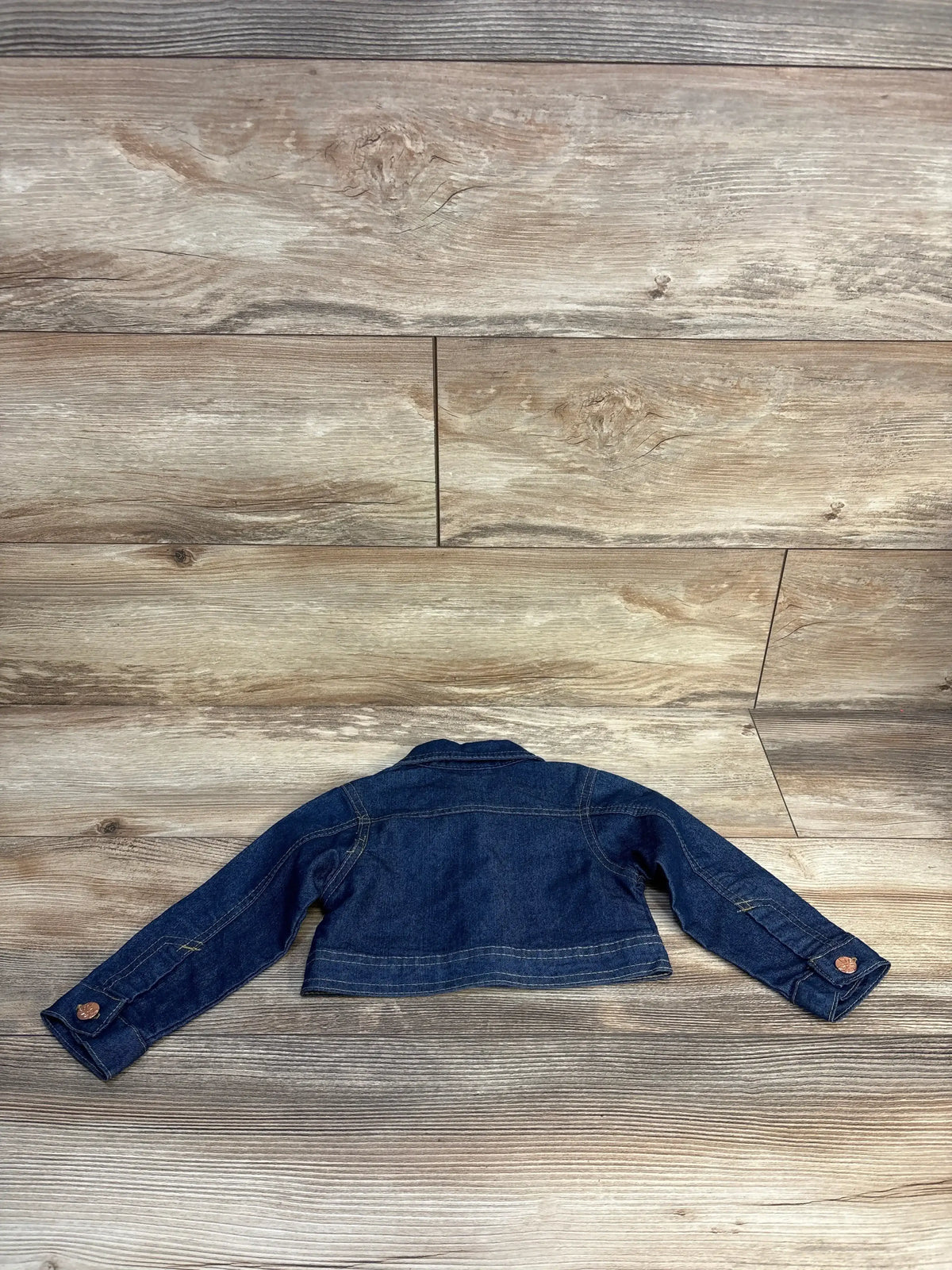 Kids dark blue denim jacket with long sleeves on wood background, back view