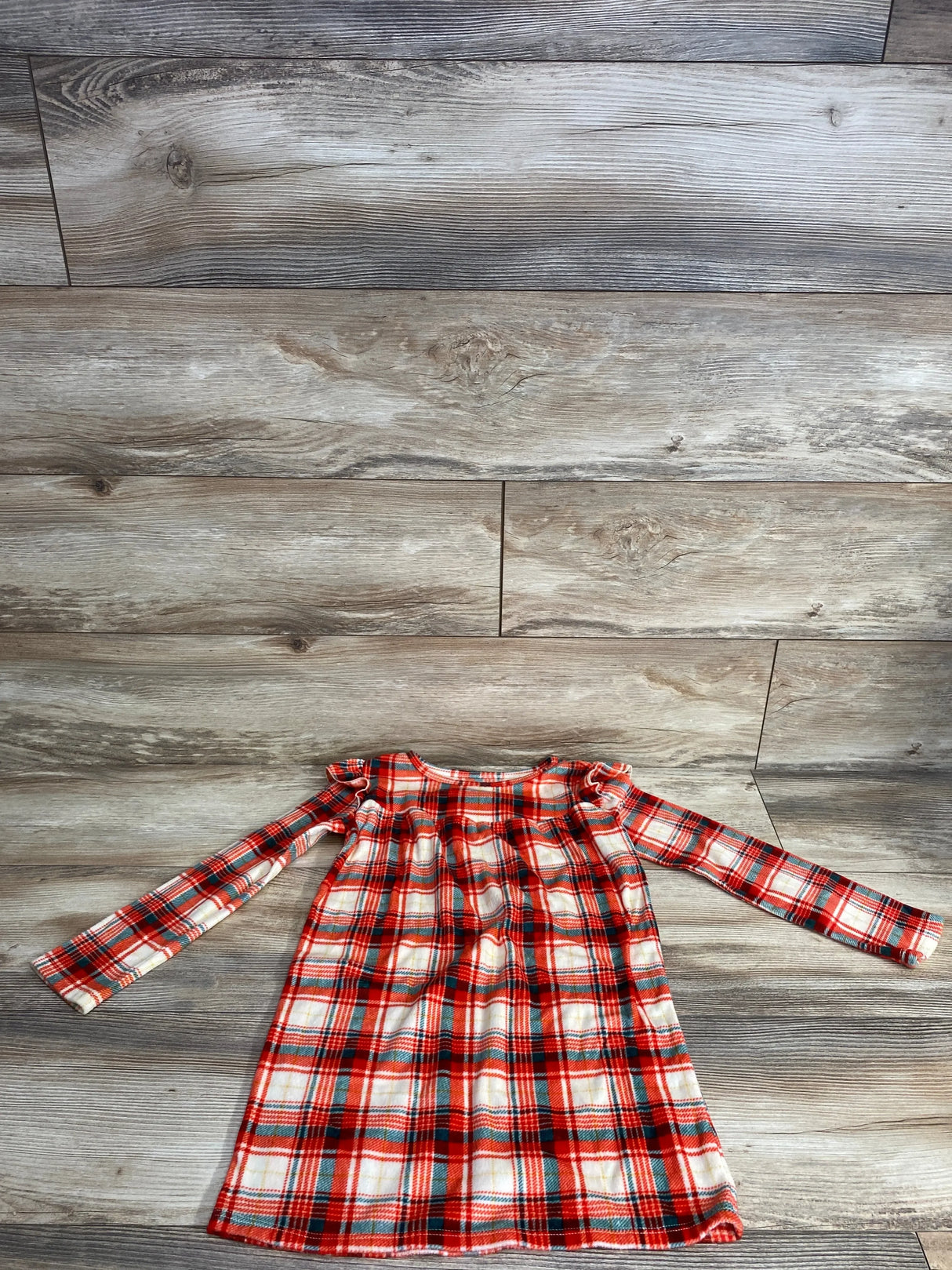 Red and white plaid long sleeve girls dress laid flat on wood floor