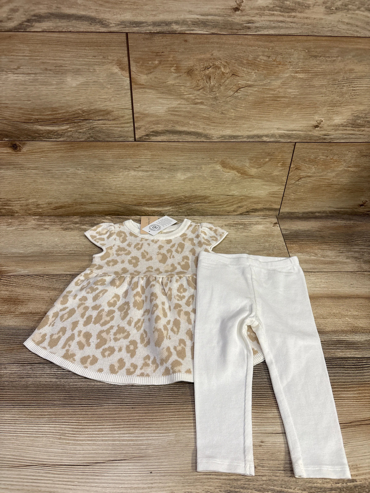Front view of First Impressions knit dress and leggings set showcasing beige leopard print dress and white leggings on wood