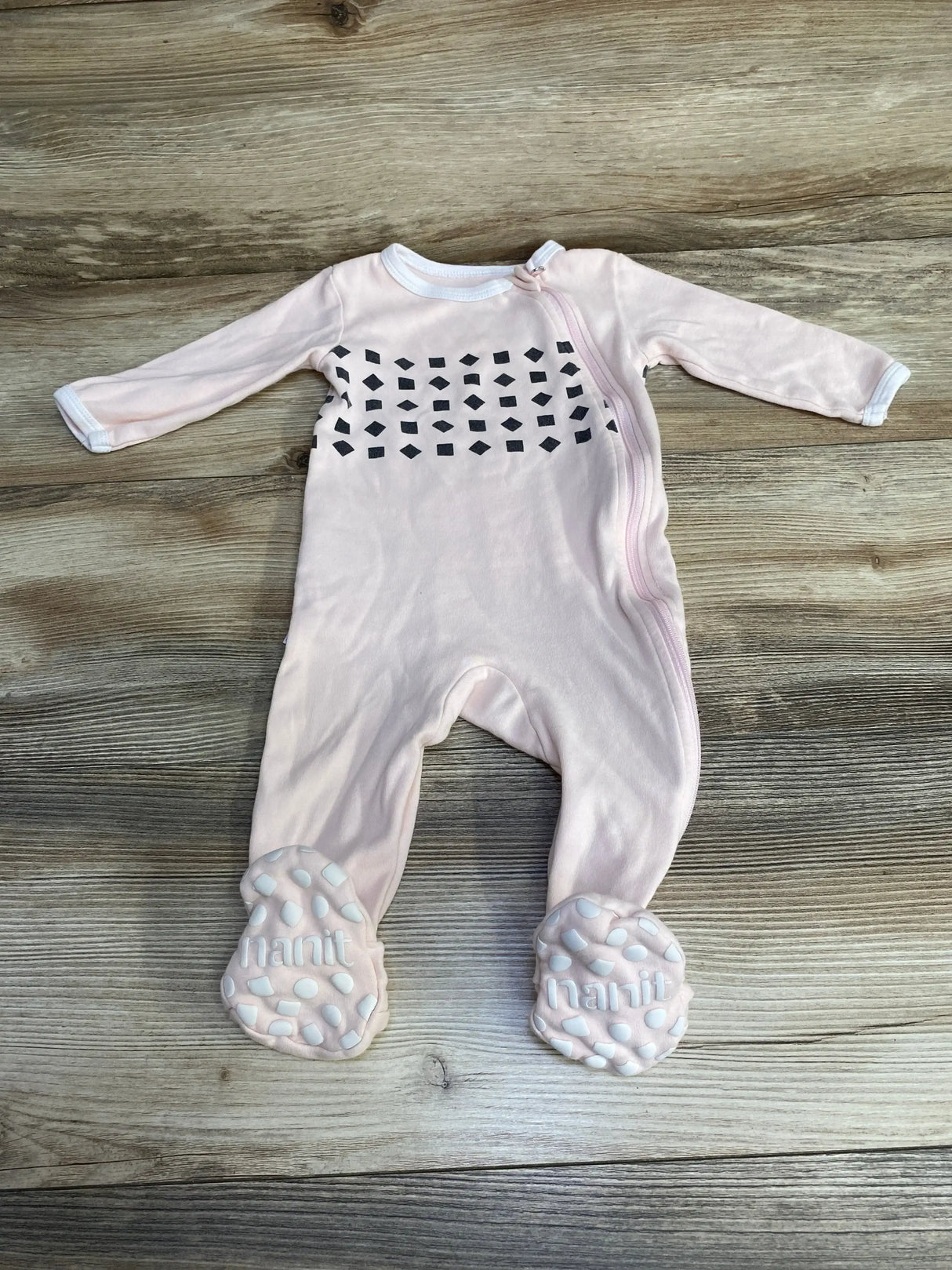 Flat-lay front of Nanit pink footed pajamas 6-9 months, diagonal zipper, black chest print and grippy foot pads