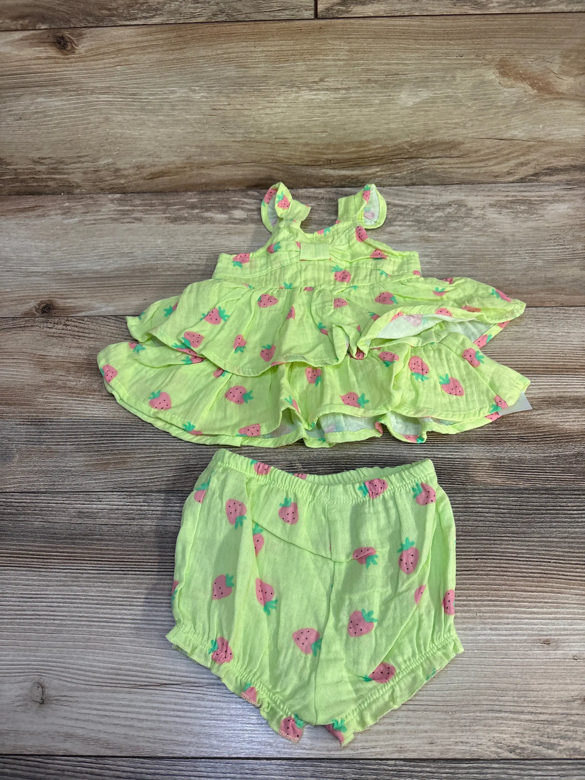 Flat lay of green Koala Baby two-piece gauze dress with ruffled layers and matching elastic-waist bloomers on wood background