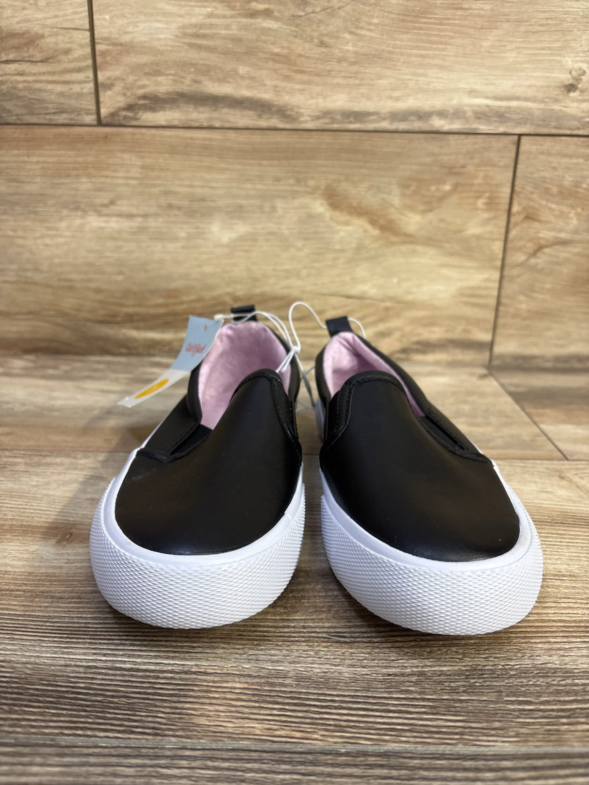 Front view of Cat & Jack Hailey black toddler slip-on sneakers showing thick white platform soles and pink lining on wood floor