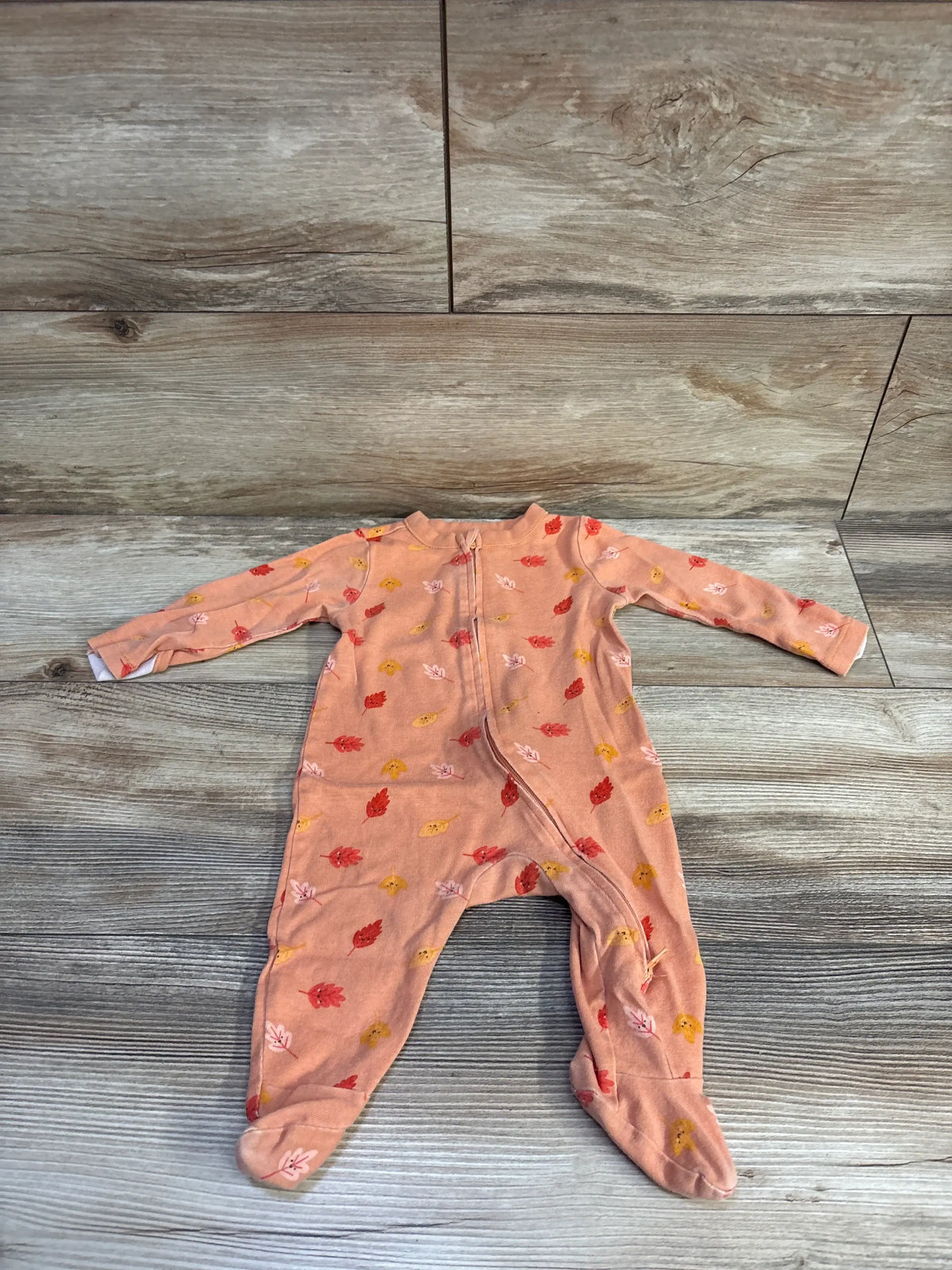 Front view of Old Navy orange leaf sleeper in 3-6 month size showcasing leaf design and two-way zipper on wood-look floor