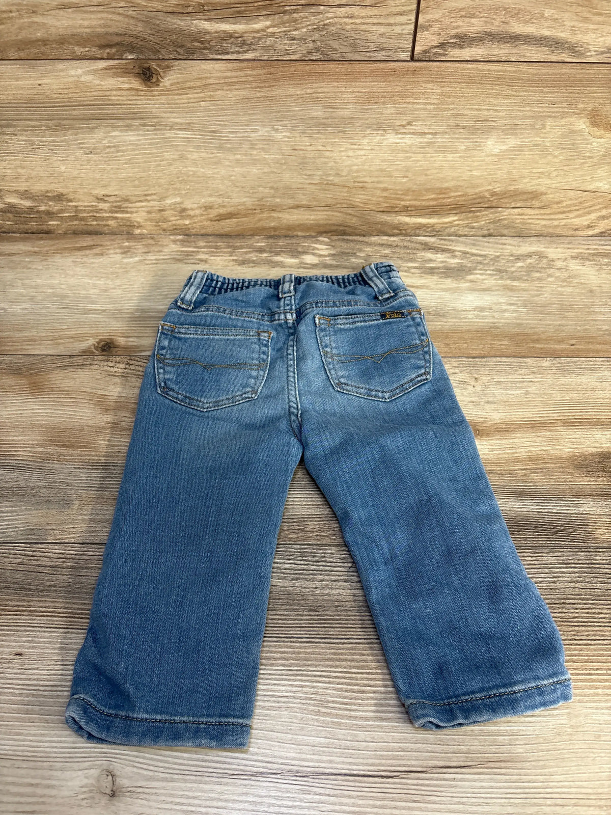 Rear view of Polo Ralph Lauren The Sullivan Slim jeans showcasing back pockets and elastic waistband on a wood surface