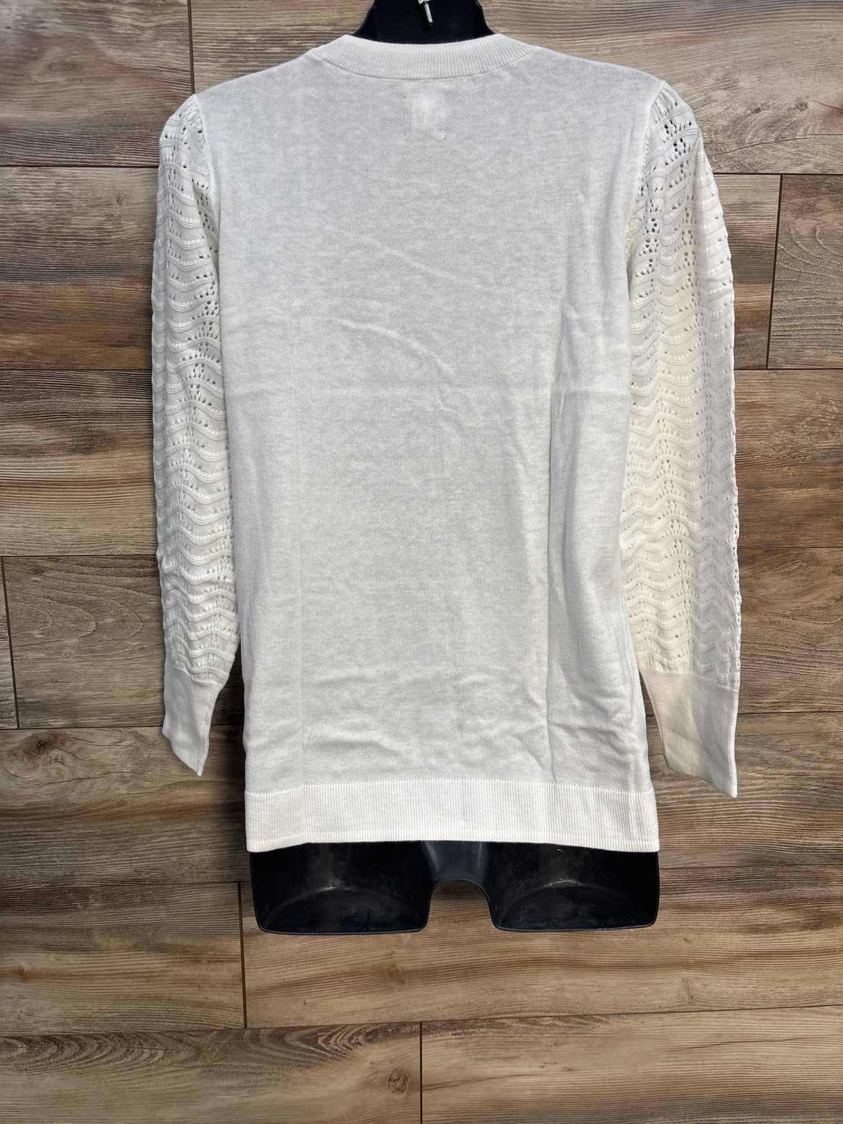 White knit sweater with textured sleeves on mannequin, wood background
