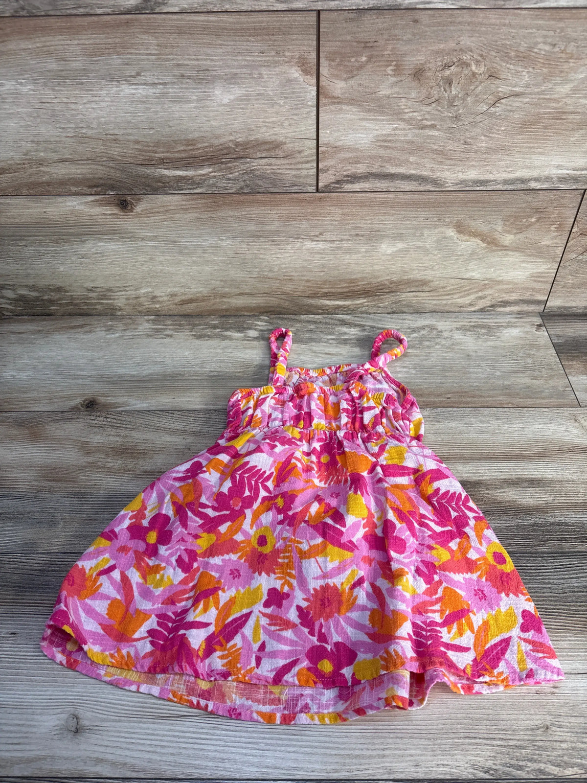 Front view of Cat & Jack pink tank dress showcasing floral print and tie shoulder straps on a woodgrain background
