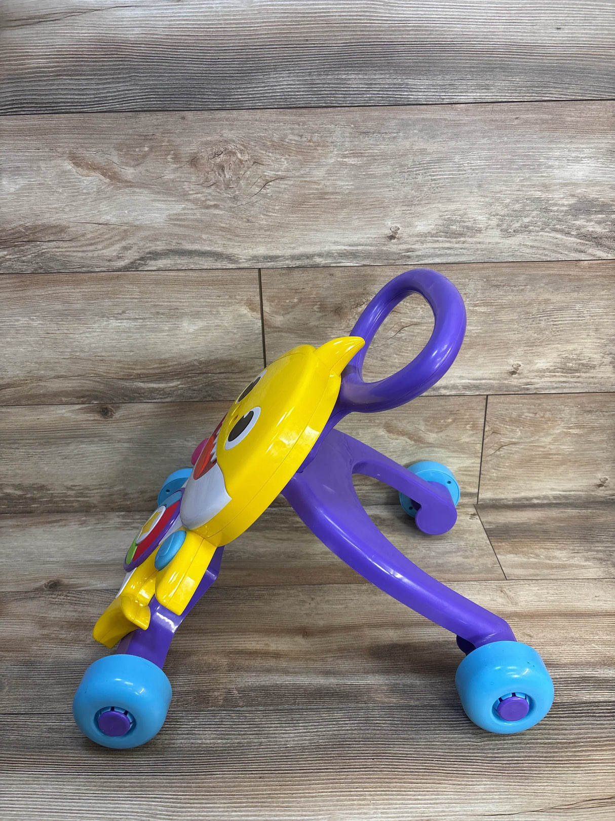 Colorful baby walker with purple handle, yellow owl design, and blue wheels on wooden floor