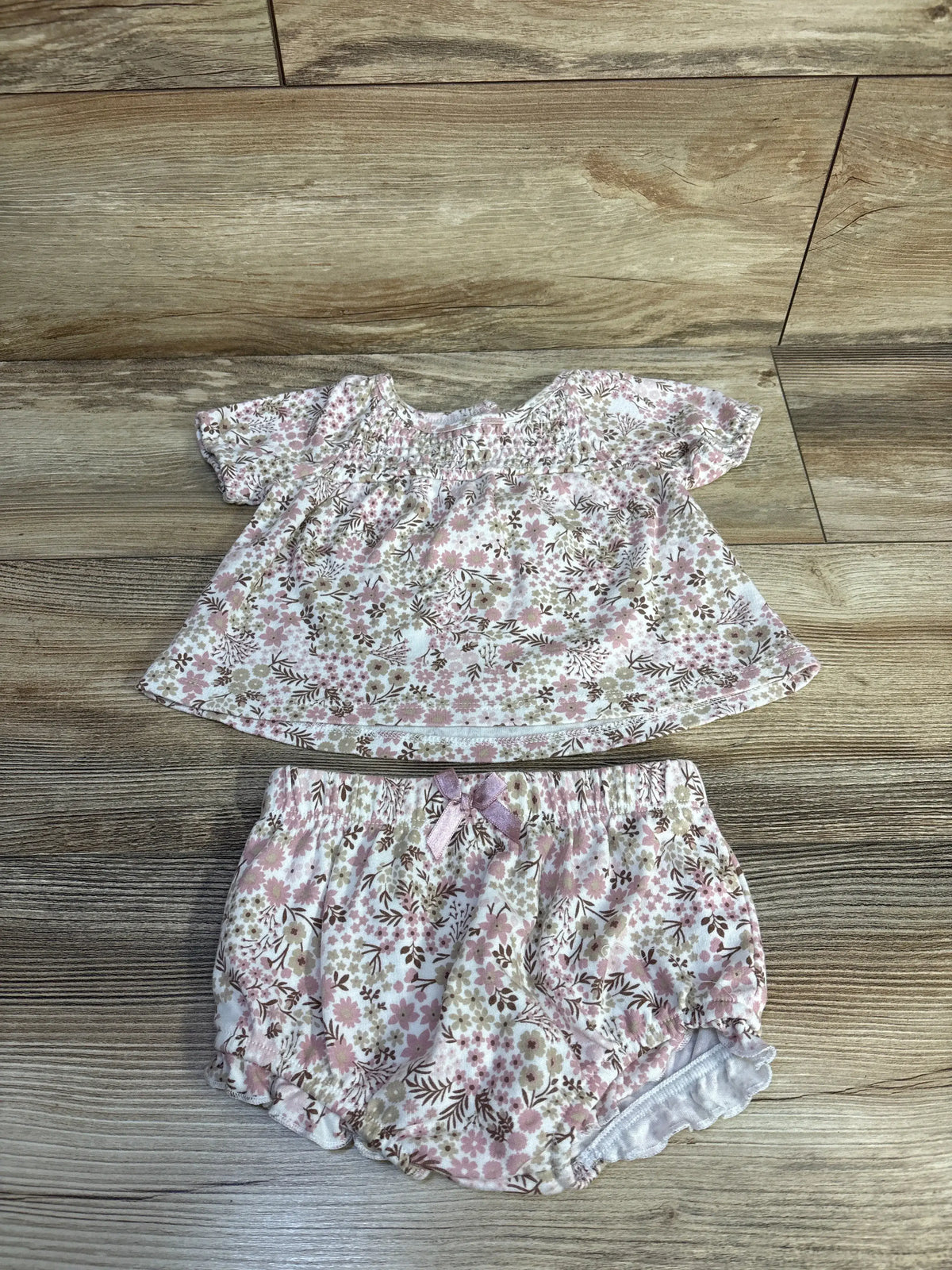 Top-down view of Nicole Miller two-piece floral top and bloomer shorts set showcasing white floral fabric on a wood floor
