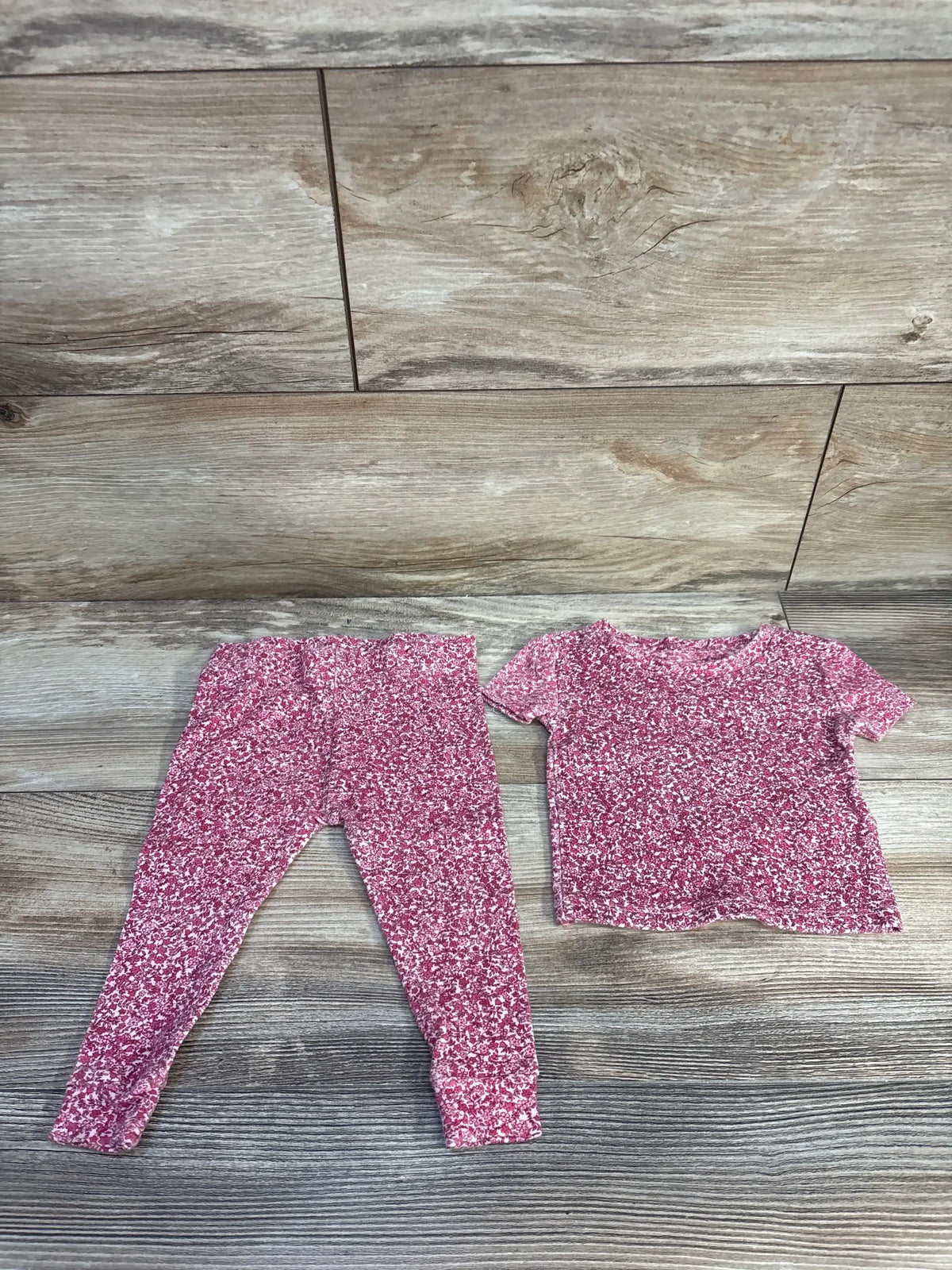 Flat lay of Penelope Mack 2-piece pink pajama showing short-sleeve top and elastic leggings with white speckle on wood floor