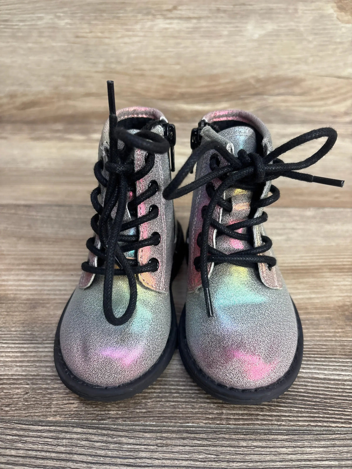 Iridescent toddler lace-up boots with black soles on wood background
