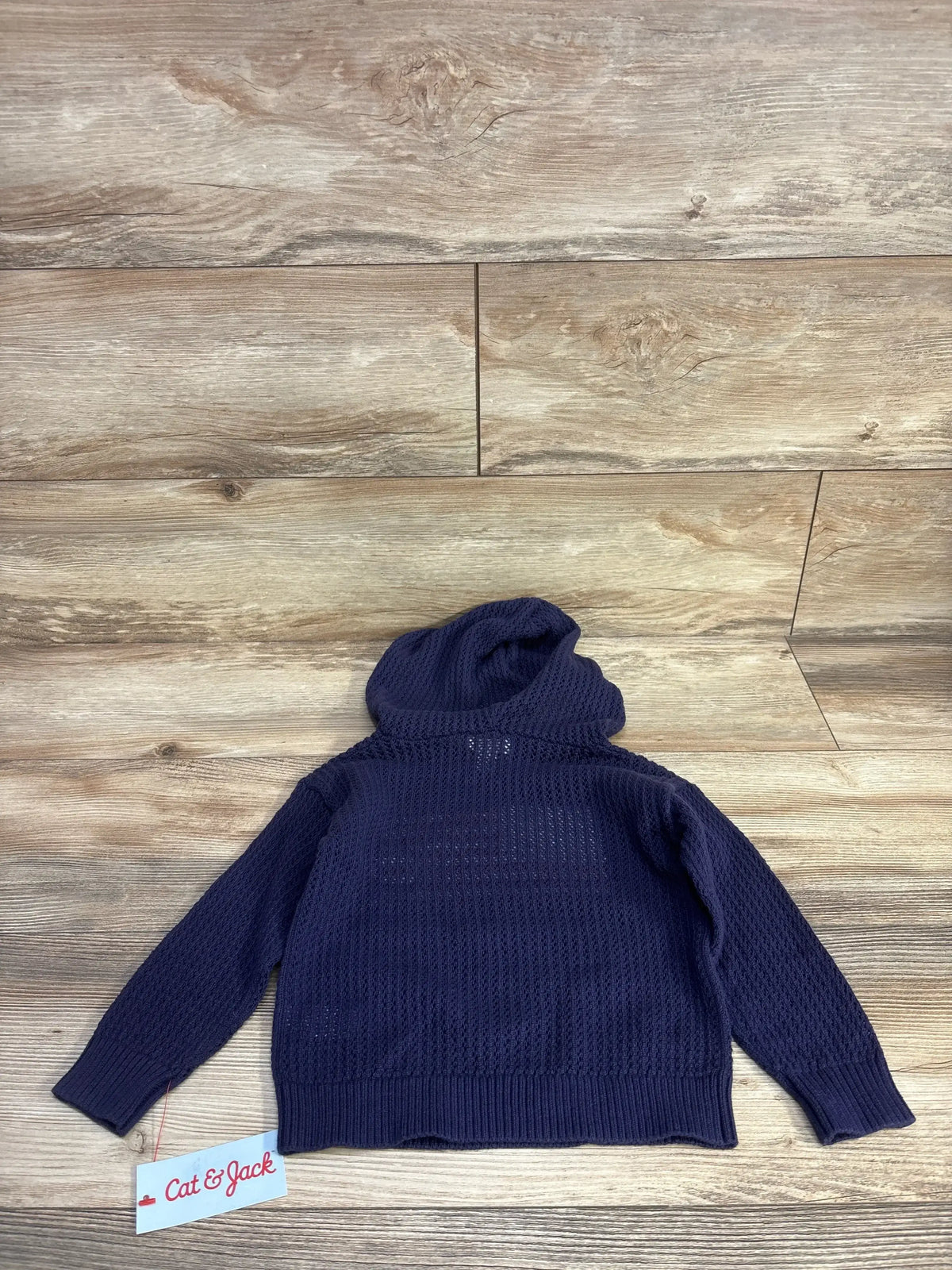 Flat lay of Cat & Jack navy toddler hooded sweater showing waffle knit texture and long sleeves on wood background