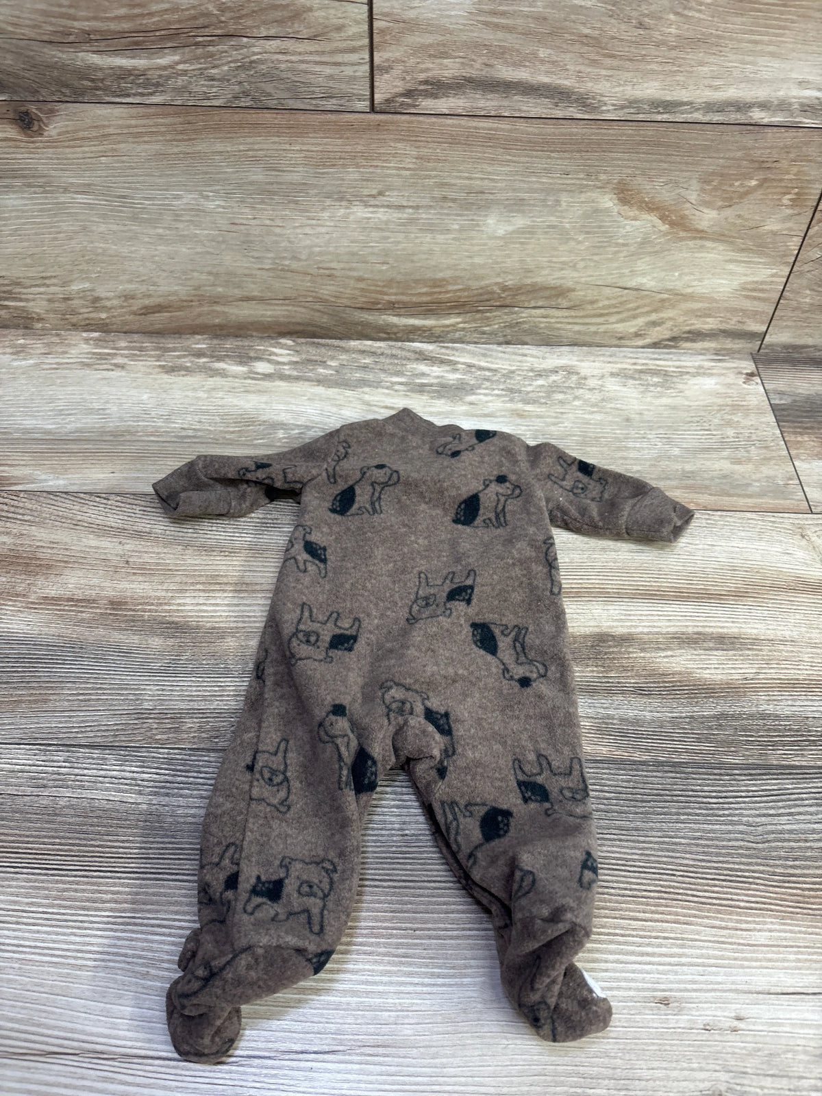 Flat lay of Child Of Mine brown preemie blanket sleeper with animal print and footed legs on a wood-look floor
