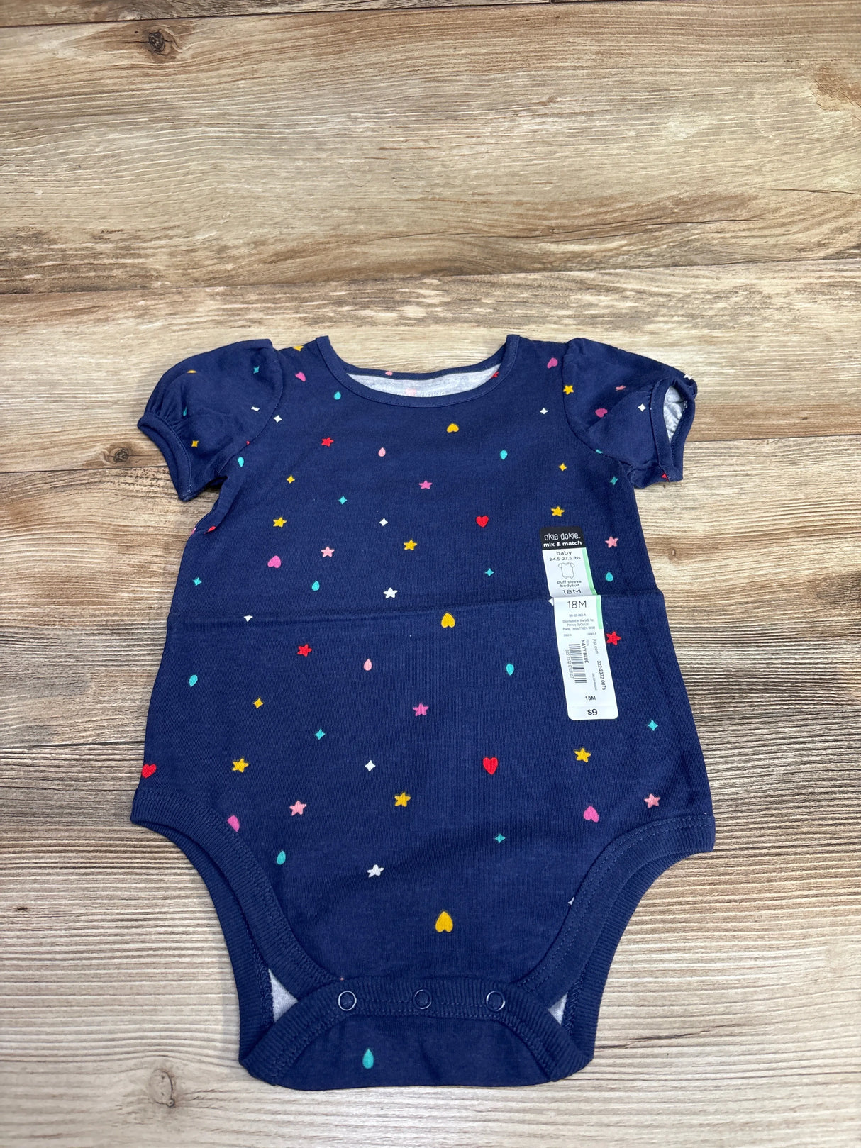 Navy blue short-sleeve baby onesie with colorful heart, star, and dot pattern, size 18M