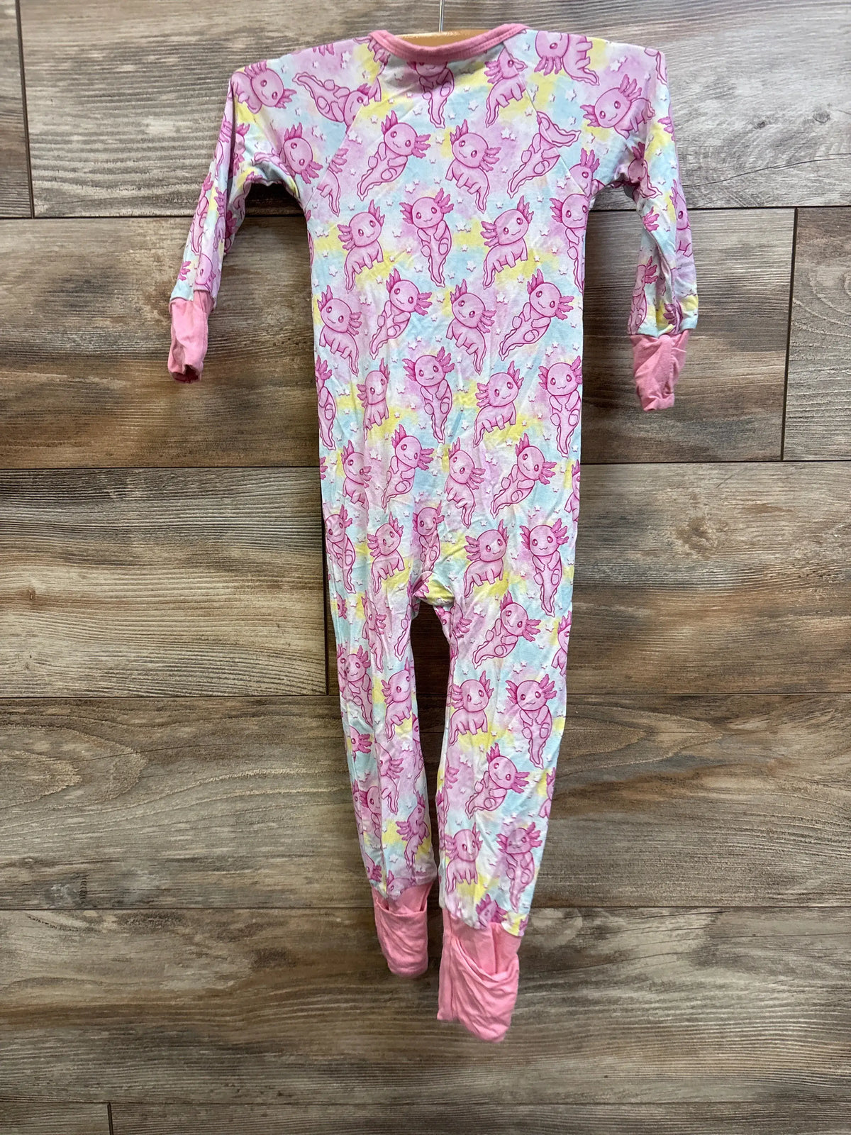 Front view of Brinley Jo bamboo convertible footie in pink with cartoon creature print and fold-over cuffs on wood flooring