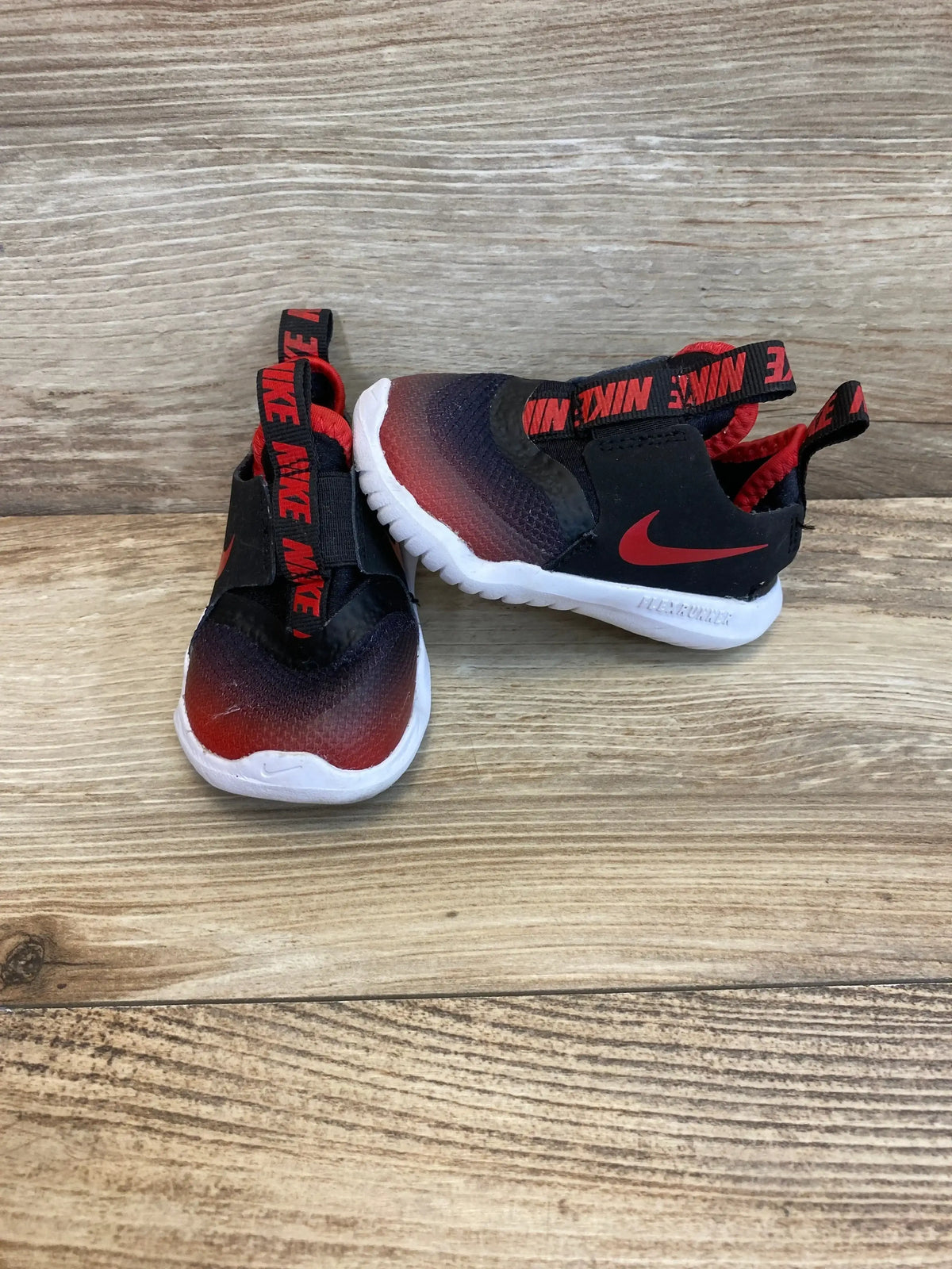 Angled view of Flex Runner TD ‘University Red Black’ sneakers sz 5c showcasing laceless design on wood background