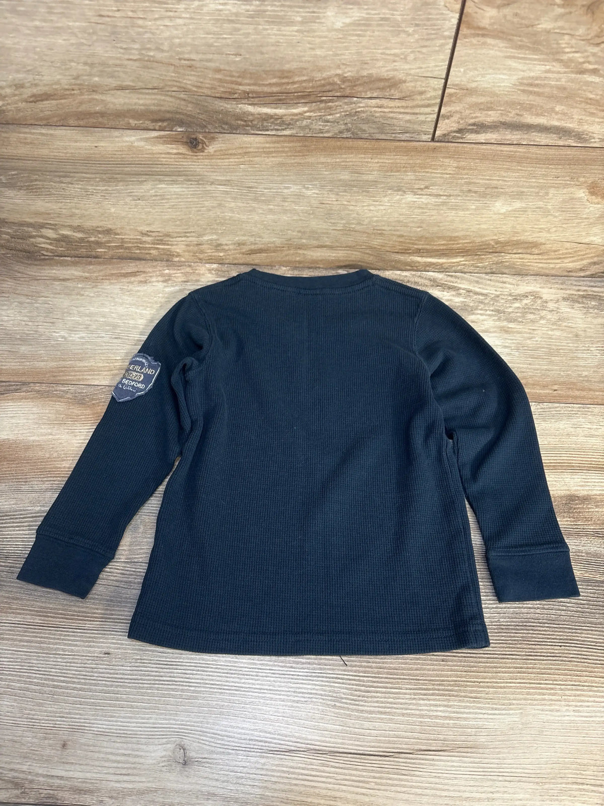 Back view of Timberland navy waffle-knit long-sleeve shirt, size 5T, showing elbow patch and waffle texture on wood background