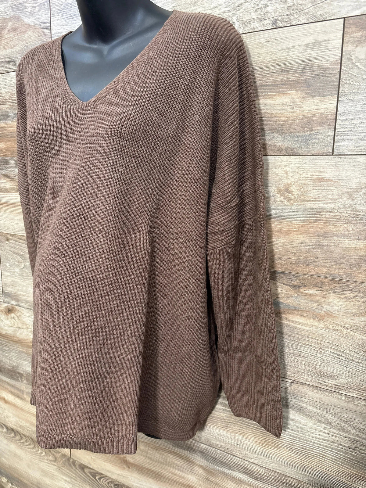 Brown ribbed knit V-neck sweater on black mannequin with wood plank background