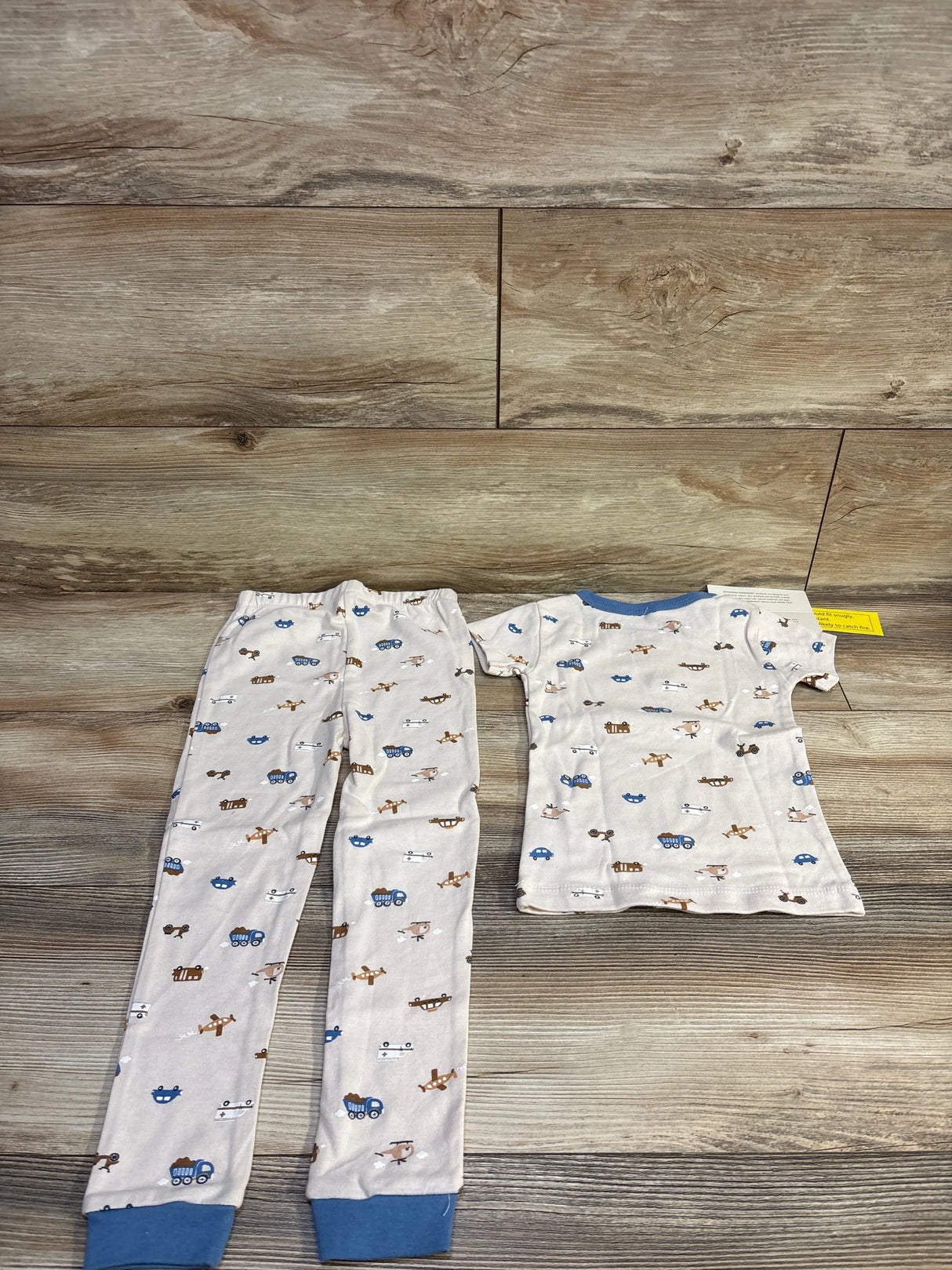 Flat-lay Chick Pea 2-piece organic pajama set, short-sleeve top and elastic pants with blue cuffs and car print on wood
