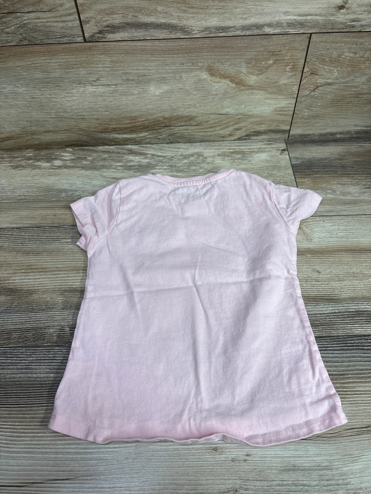 Back view of a light pink Tucker + Tate children's short sleeve shirt on a wooden surface.