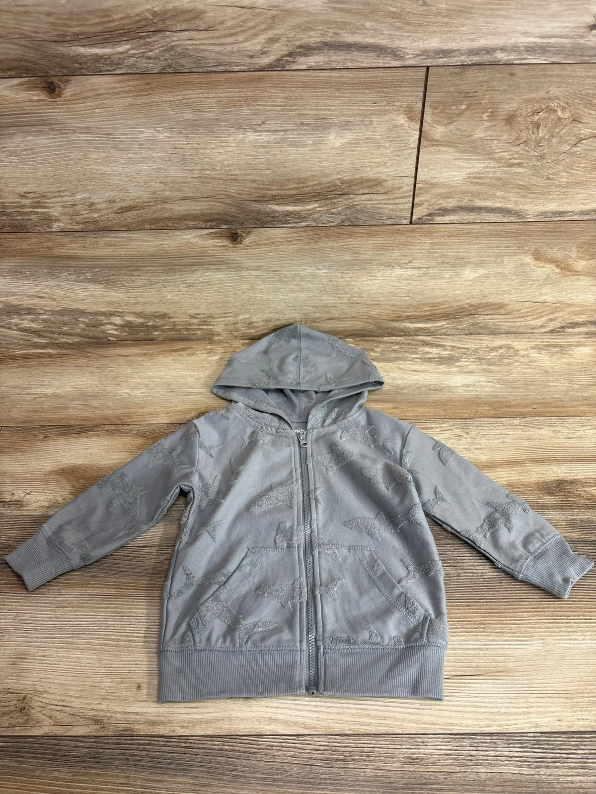 Flat-lay of grey Jumping Beans full-zip hooded toddler jacket size 18 months showing shark pattern on wood floor background