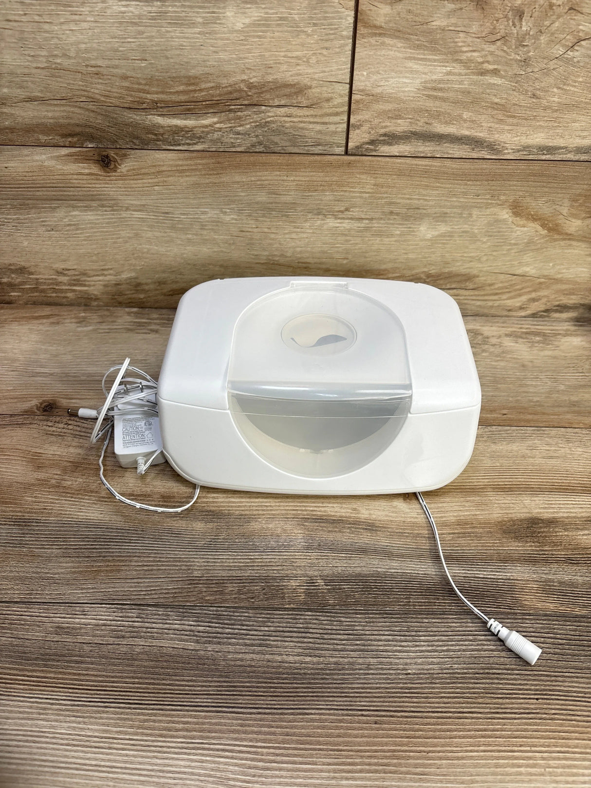 Front view of Munchkin Bright & Warm wipe warmer showcasing translucent flip lid and included power adapter on wooden tabletop background
