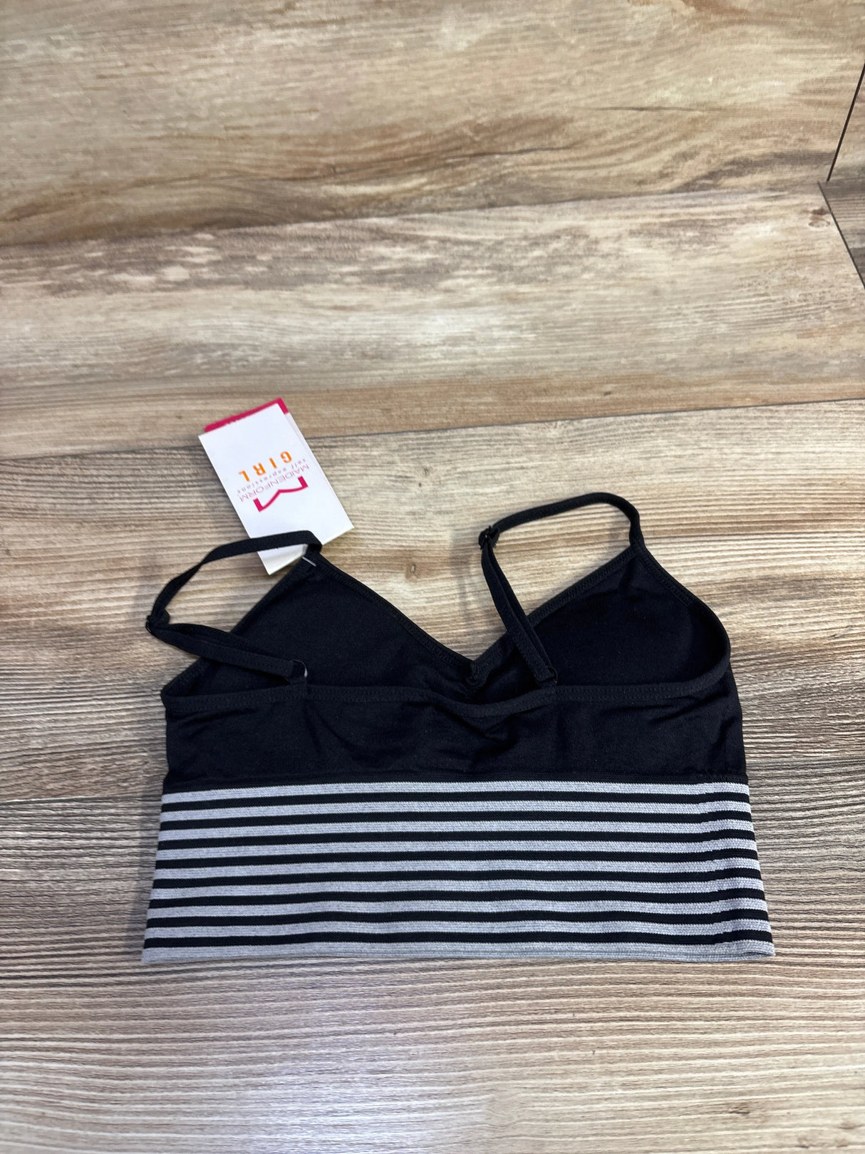 Black and gray striped bralette with thin straps on wooden surface