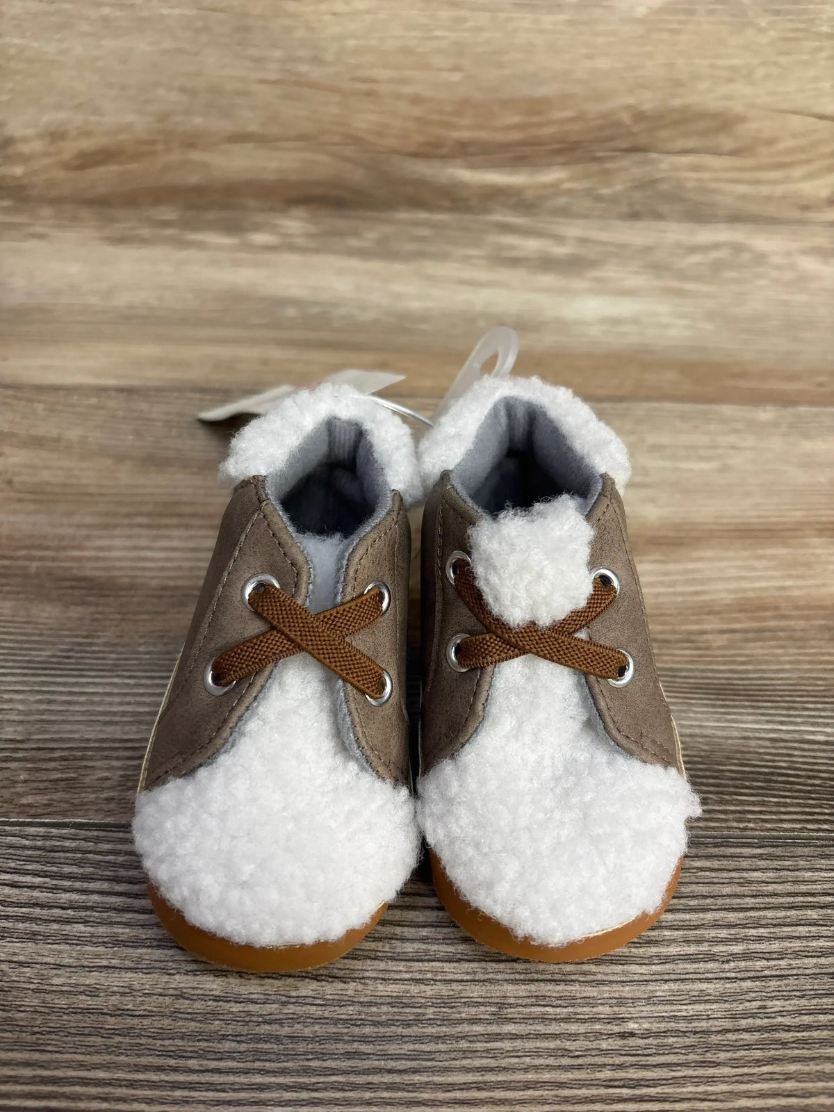 Front view of Cat and Jack Sherpa high-top crib shoes showcasing white sherpa fleece lining and brown faux-suede upper on wood surface