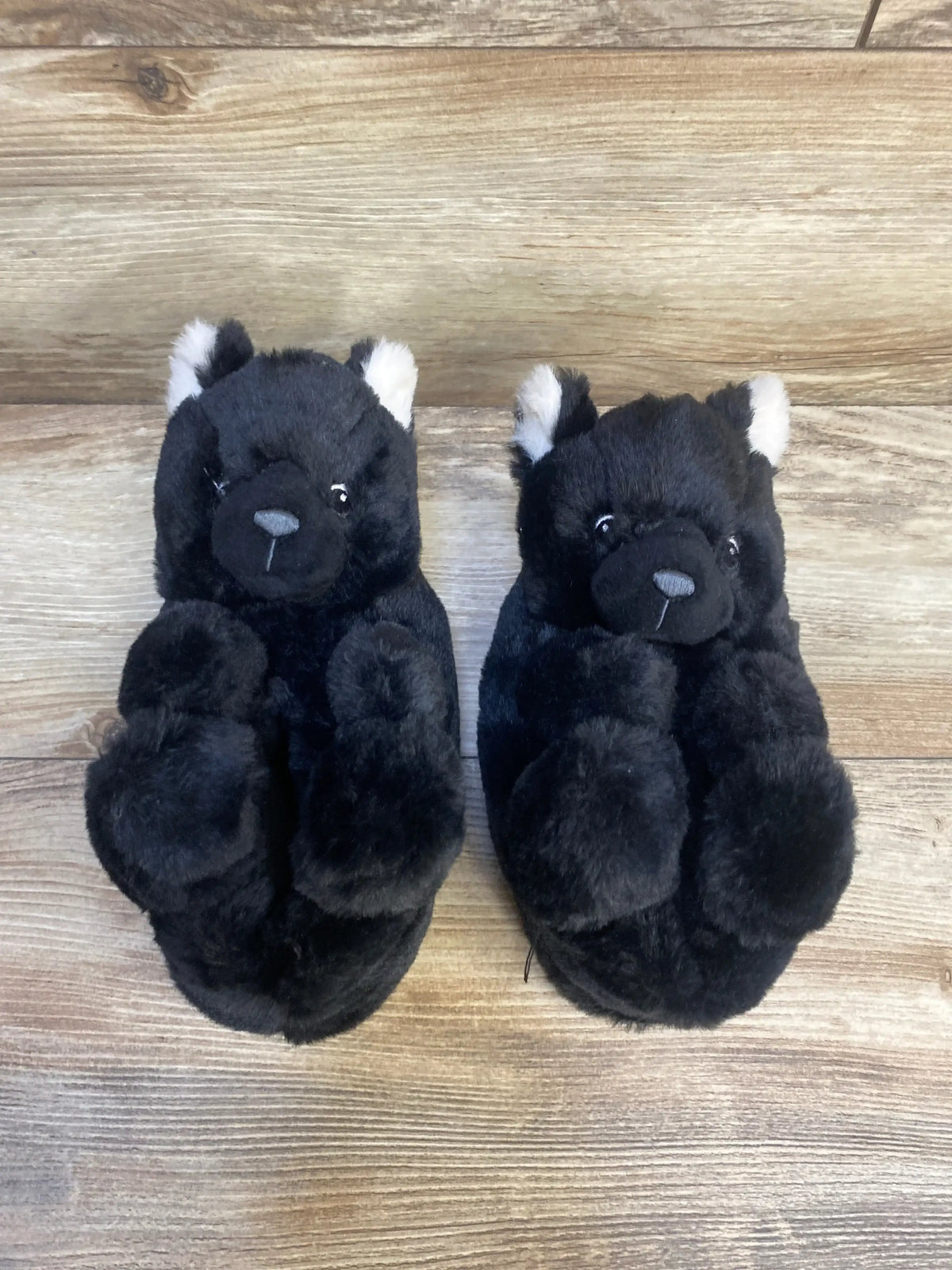 Plush black bear kids slippers with white ears on wooden floor