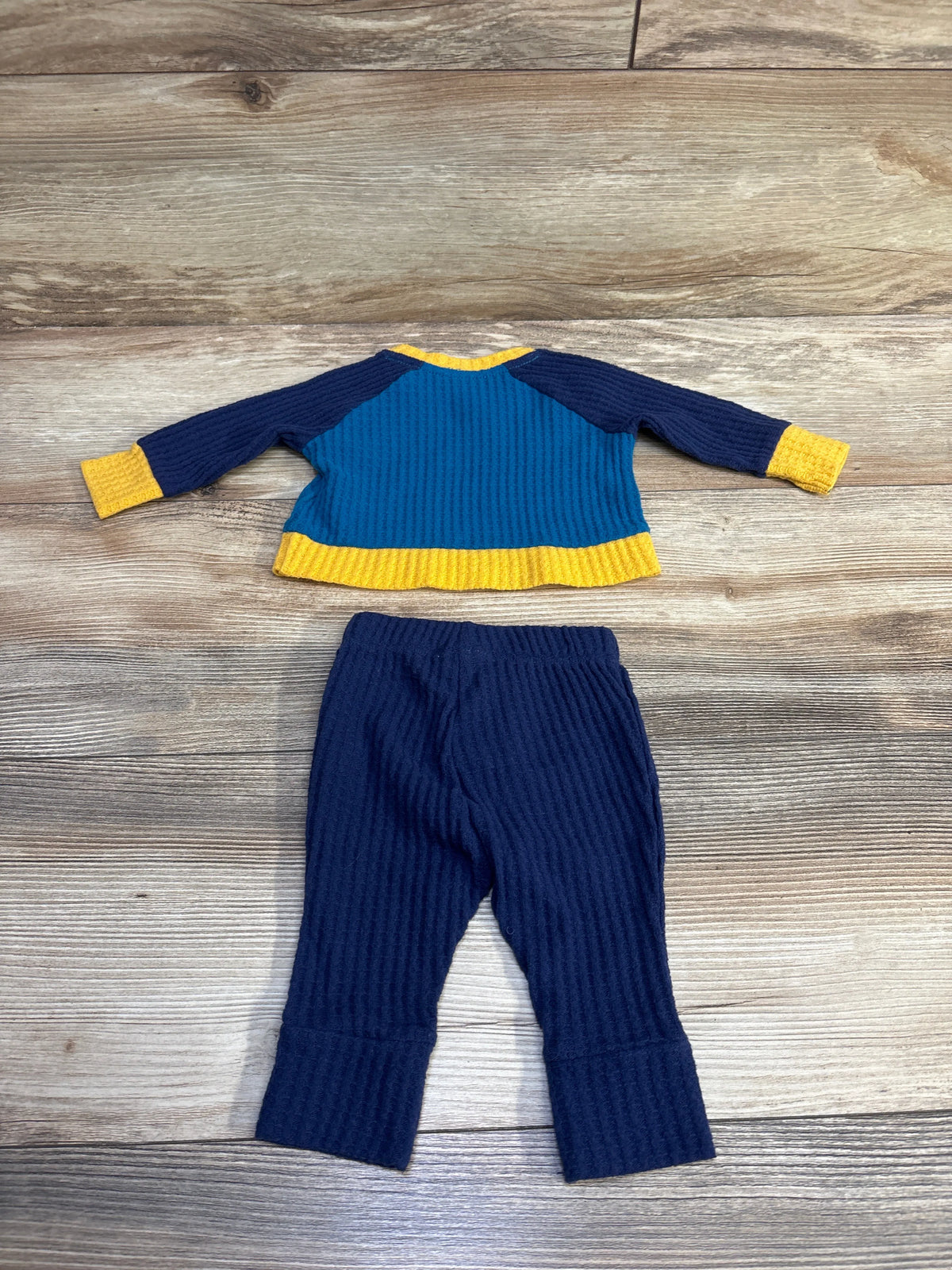 Front view of Cat & Jack waffle-knit shirt and pants set showing yellow trim and cuffs on a wood-grain background