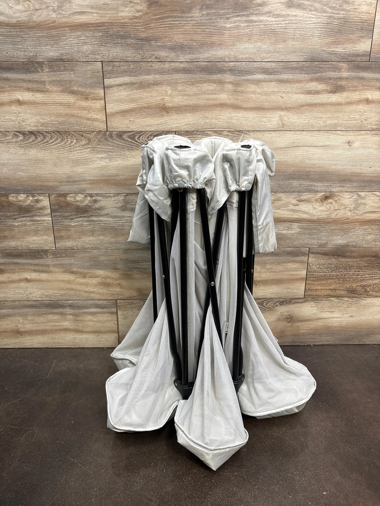 Folded white mesh laundry hamper with black frame on wood background