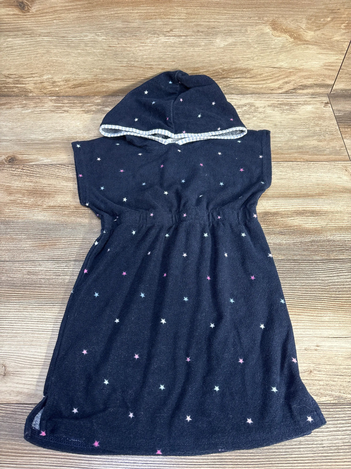 Top view of Crown + Ivy Kids navy terry cloth swim cover up with star pattern and white-trimmed hood on wood floor