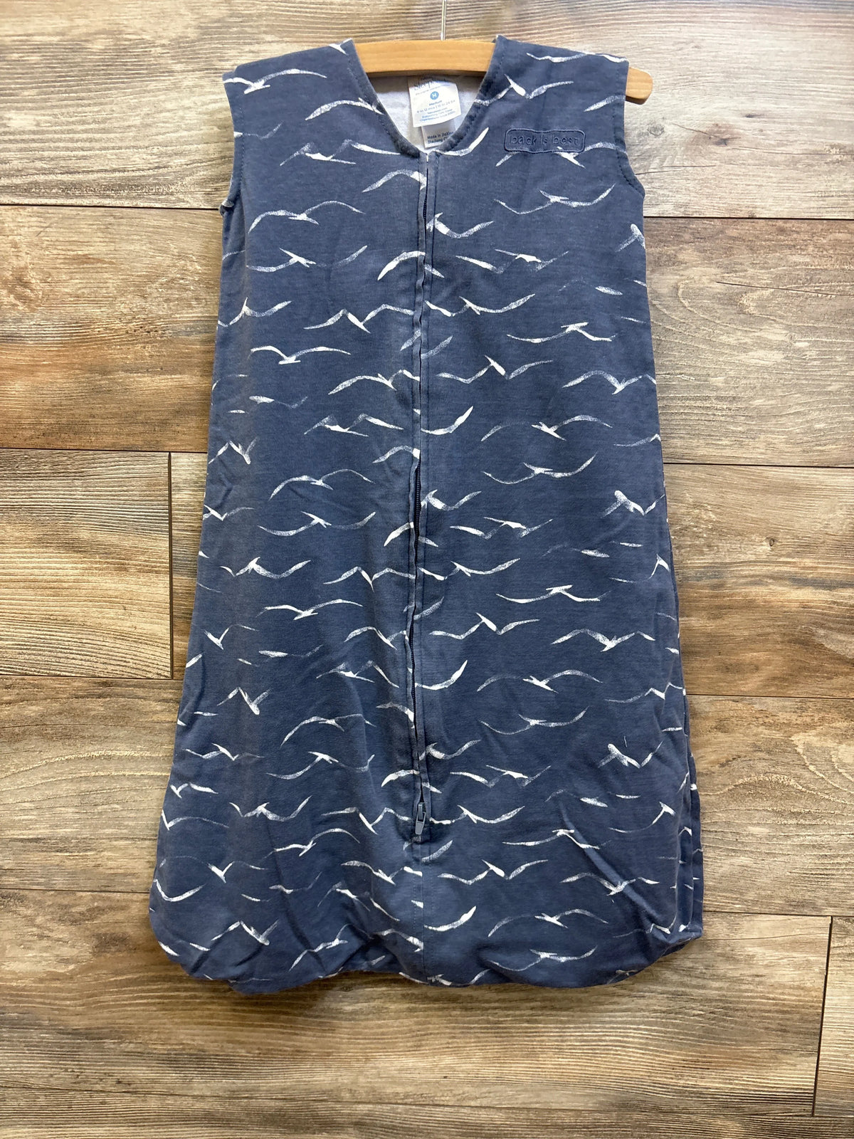 Front view of Halo SleepSack in grey with white bird pattern, full-length zipper, and rounded bottom on a wooden background