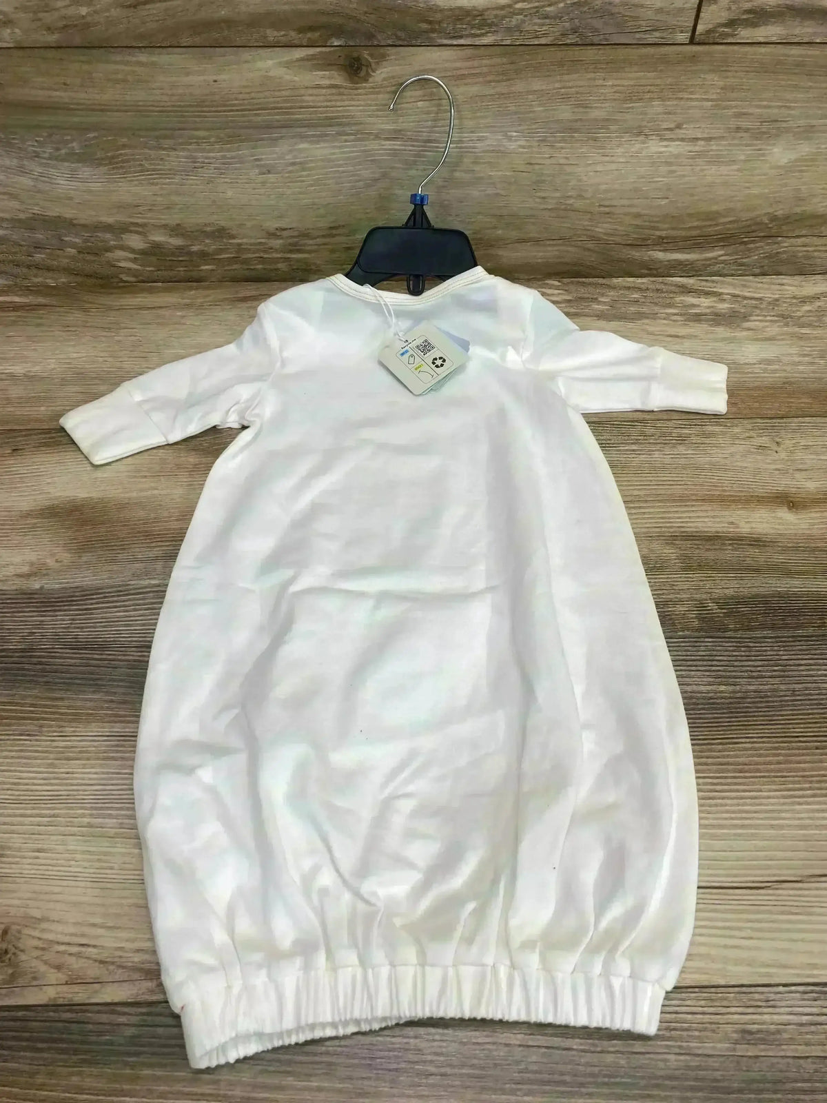 Flat-lay back view of Bunnies By The Bay Skipit’s white baby gown 0-3M showing long sleeves and elastic gathered hem on wood planks
