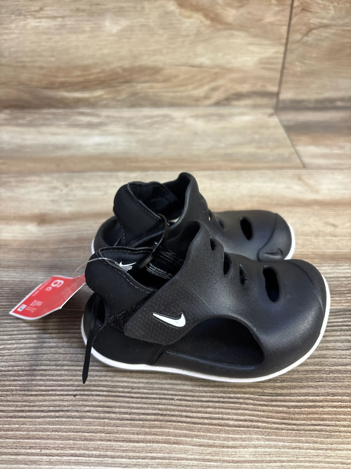 Three-quarter view of black Nike Sunray Protect 3 sandals showcasing adjustable straps and open design on a wood-grain surface
