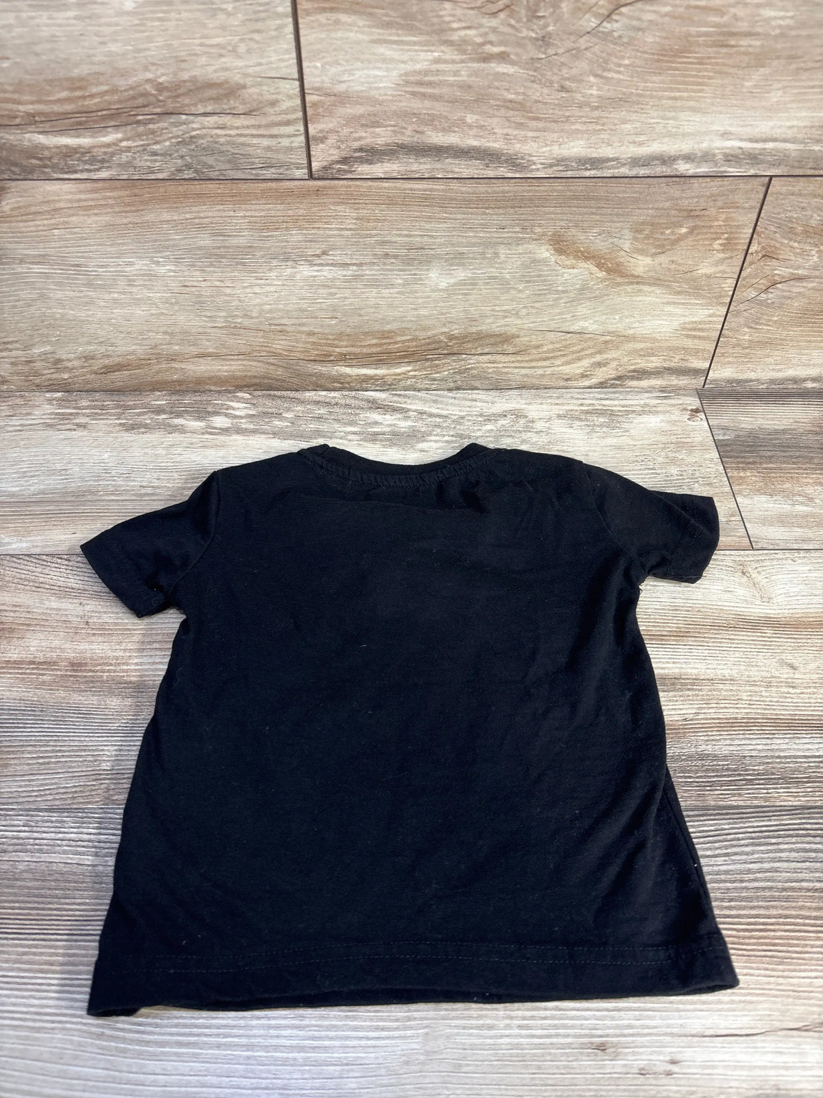 Front view of True Religion black toddler shirt in size 4T showcasing short sleeves and relaxed fit on a wood-look floor
