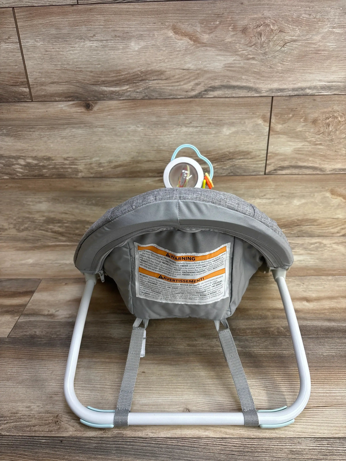 Rear view of NEW Skip Hop Silver Lining Cloud upright floor seat showing gray padded support, white frame, and attached toy