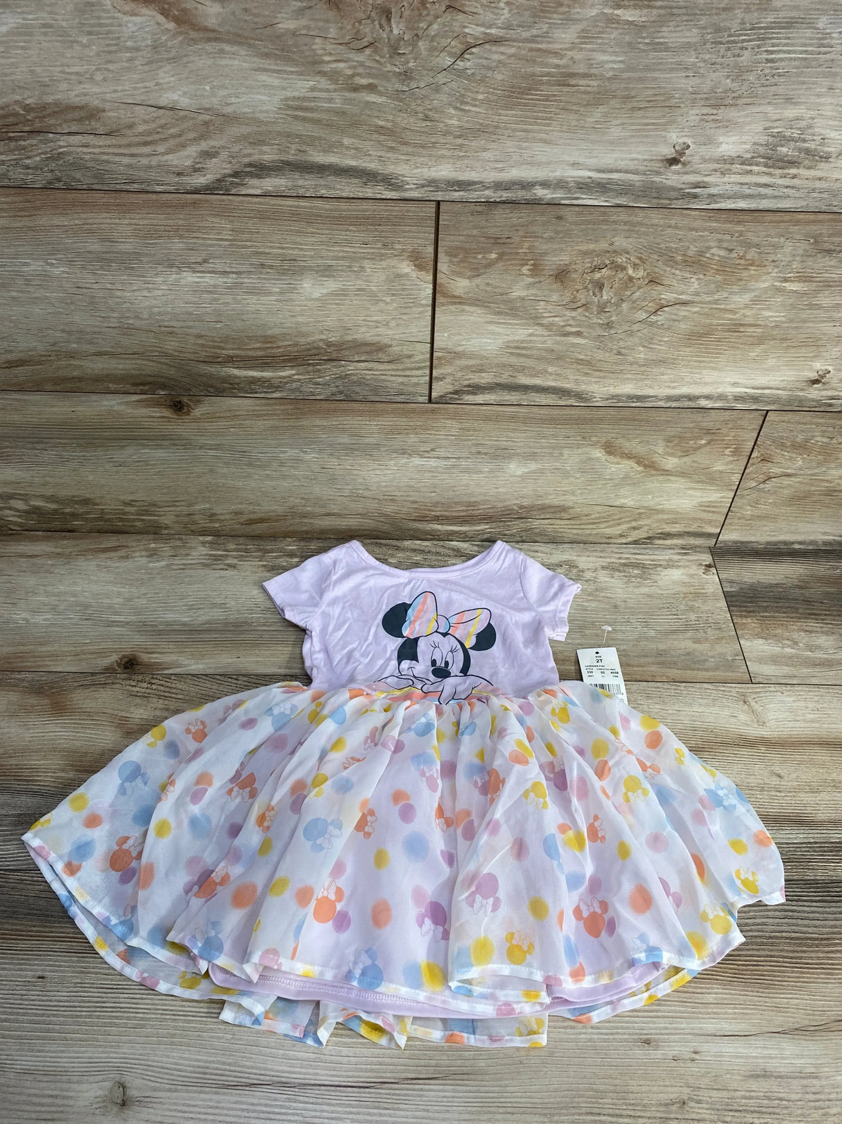 Pink Minnie Mouse toddler dress with pastel polka dots and tutu skirt on wood floor