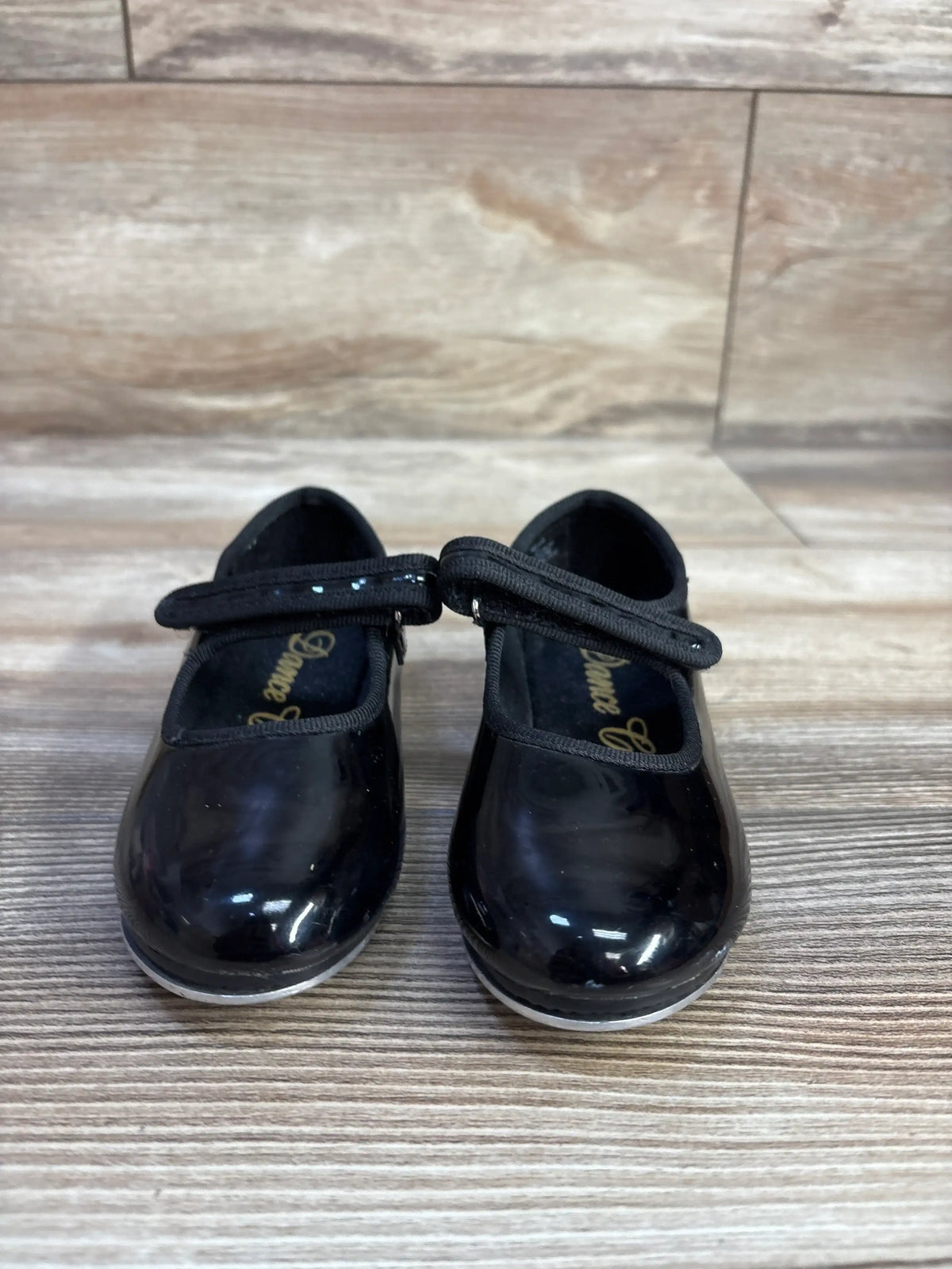 Front view of black tap shoes in size 7.5c showcasing Mary Jane straps and tap plates on a wood floor