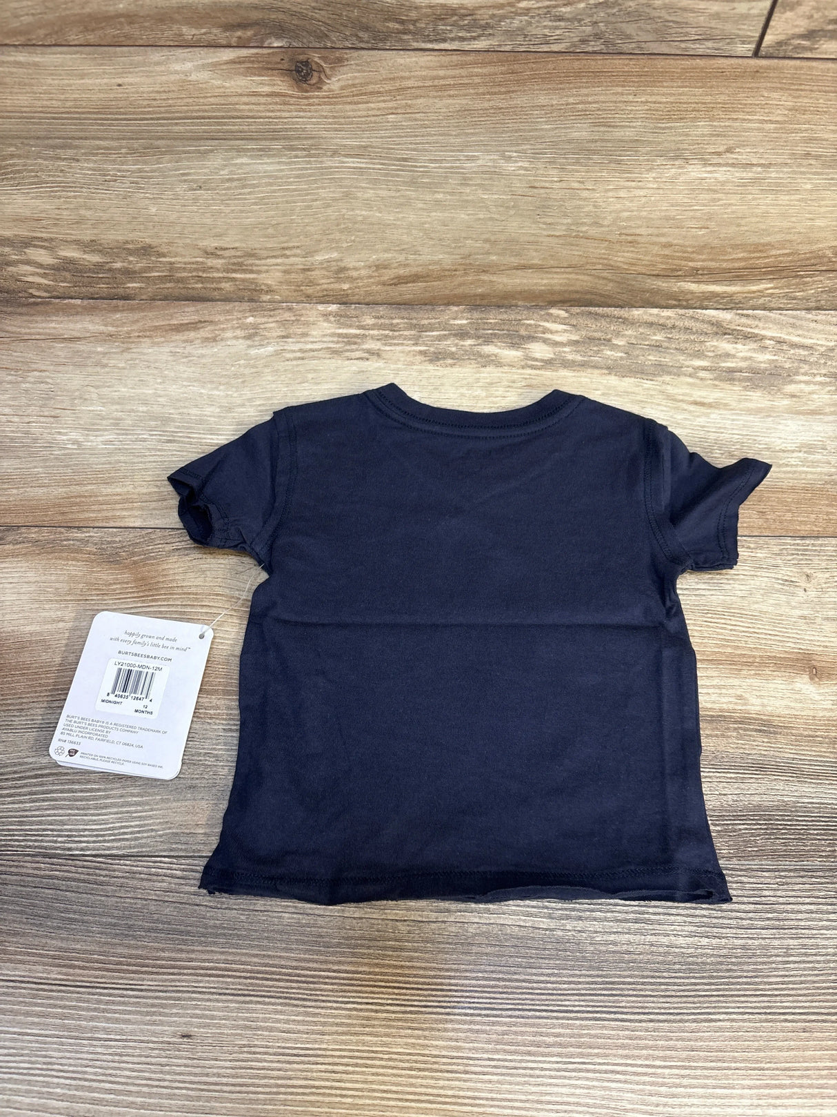 Back view of navy Burt's Bees Baby short-sleeve raw hem shirt, 12 months, showing attached tag on wood floor