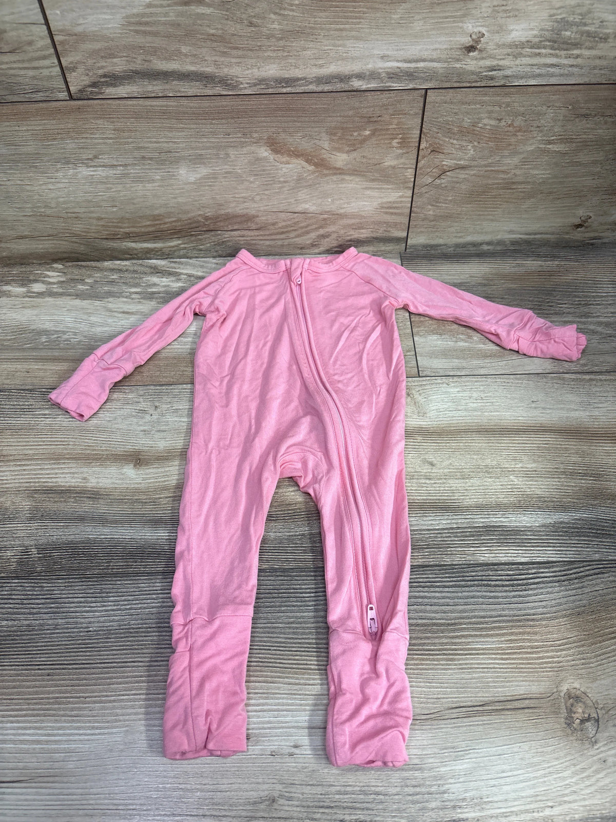 Top view of Suzel pink bamboo convertible sleeper with full-length zipper and covered feet, laid flat on wood-look flooring
