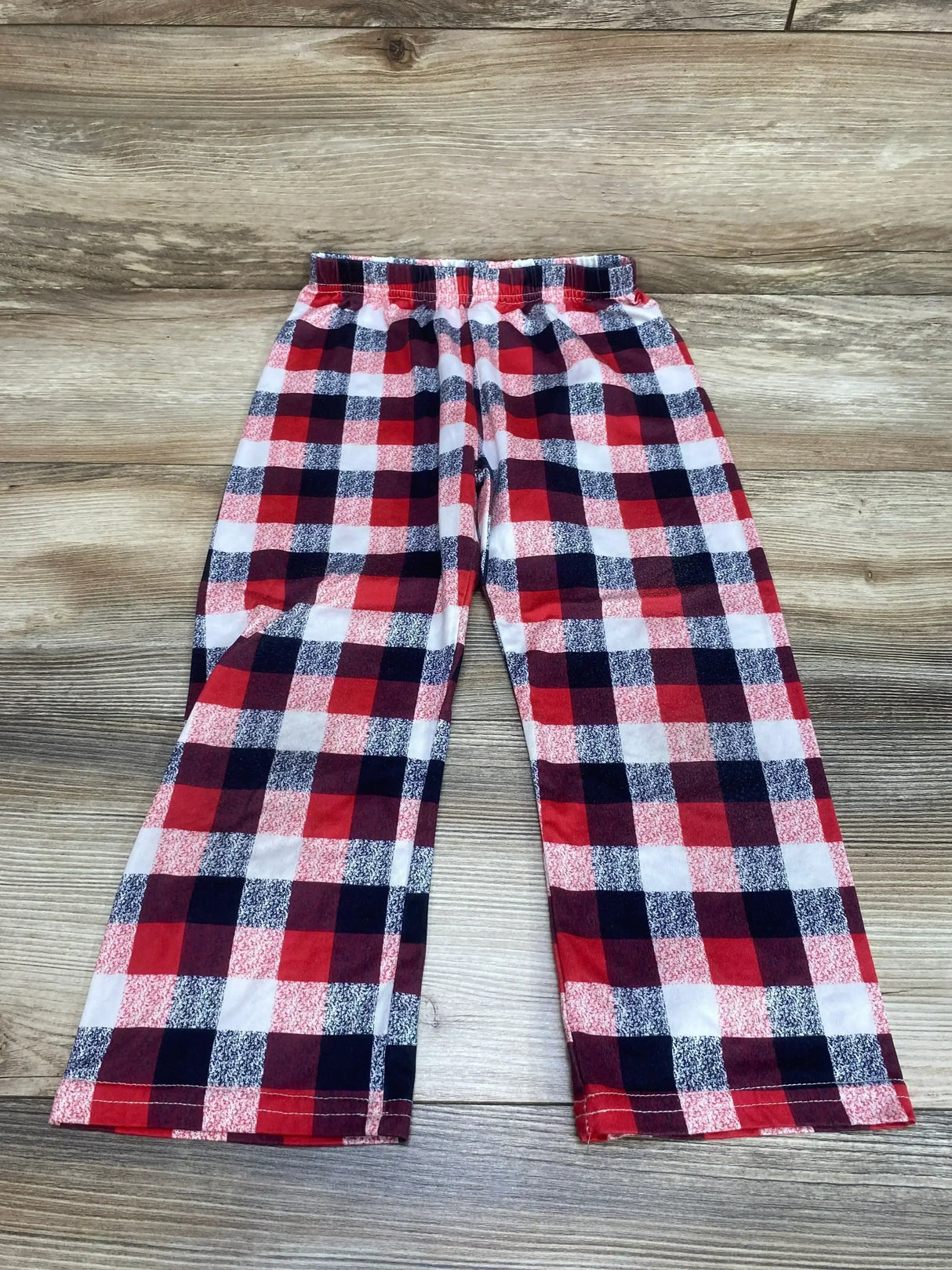 Flat lay of red and navy plaid toddler pants size 4T showing elastic waistband and straight legs on wood background