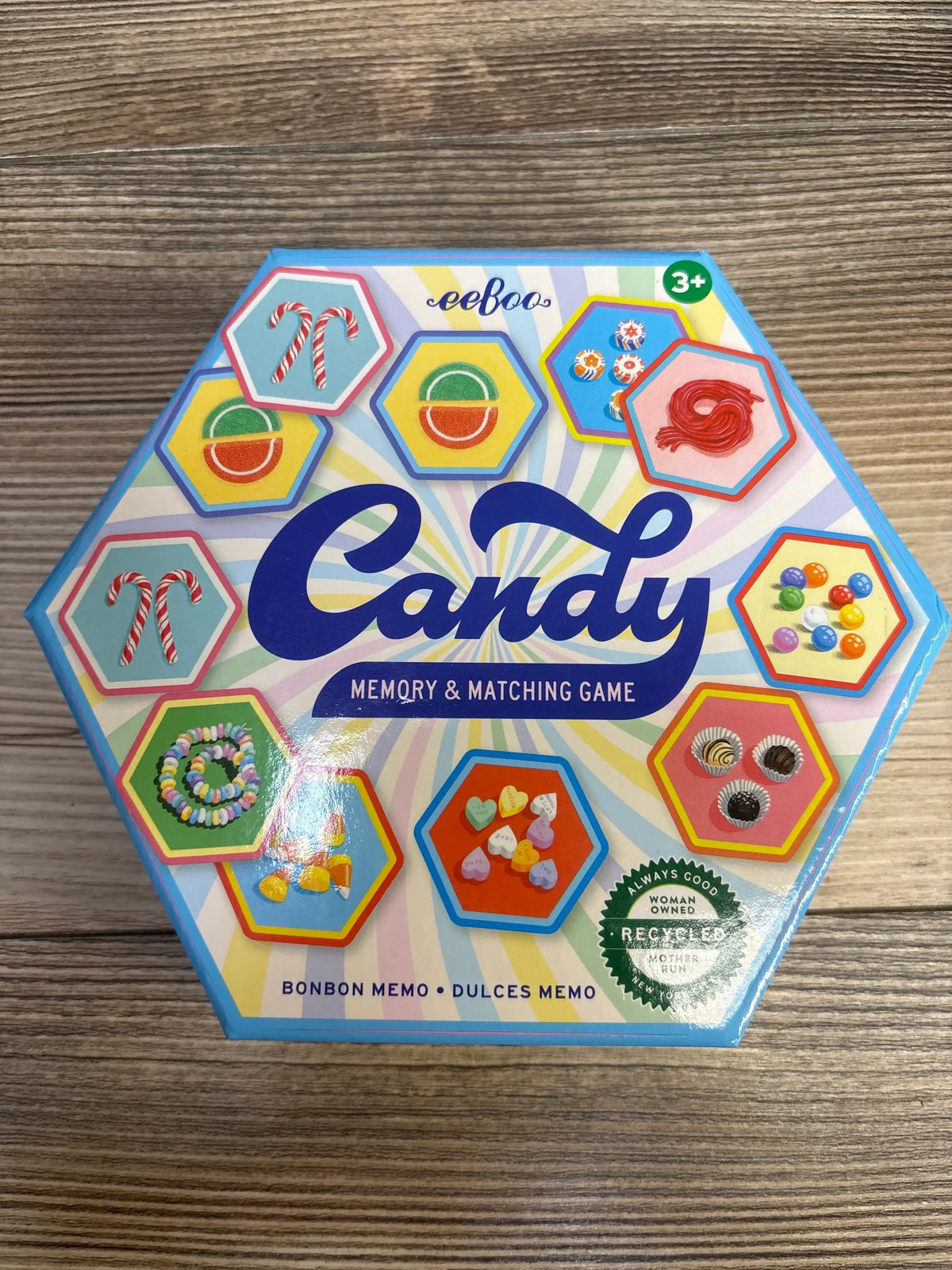 Top-down view of eeboo Candy memory and matching game hexagon box with colorful candy illustrations and large Candy title on wood background