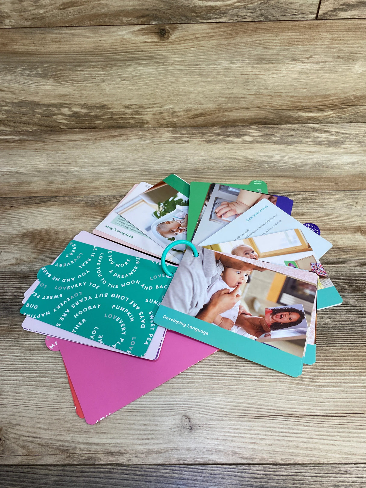 Baby development flashcards on a wooden table with images of infants and caregiving tips