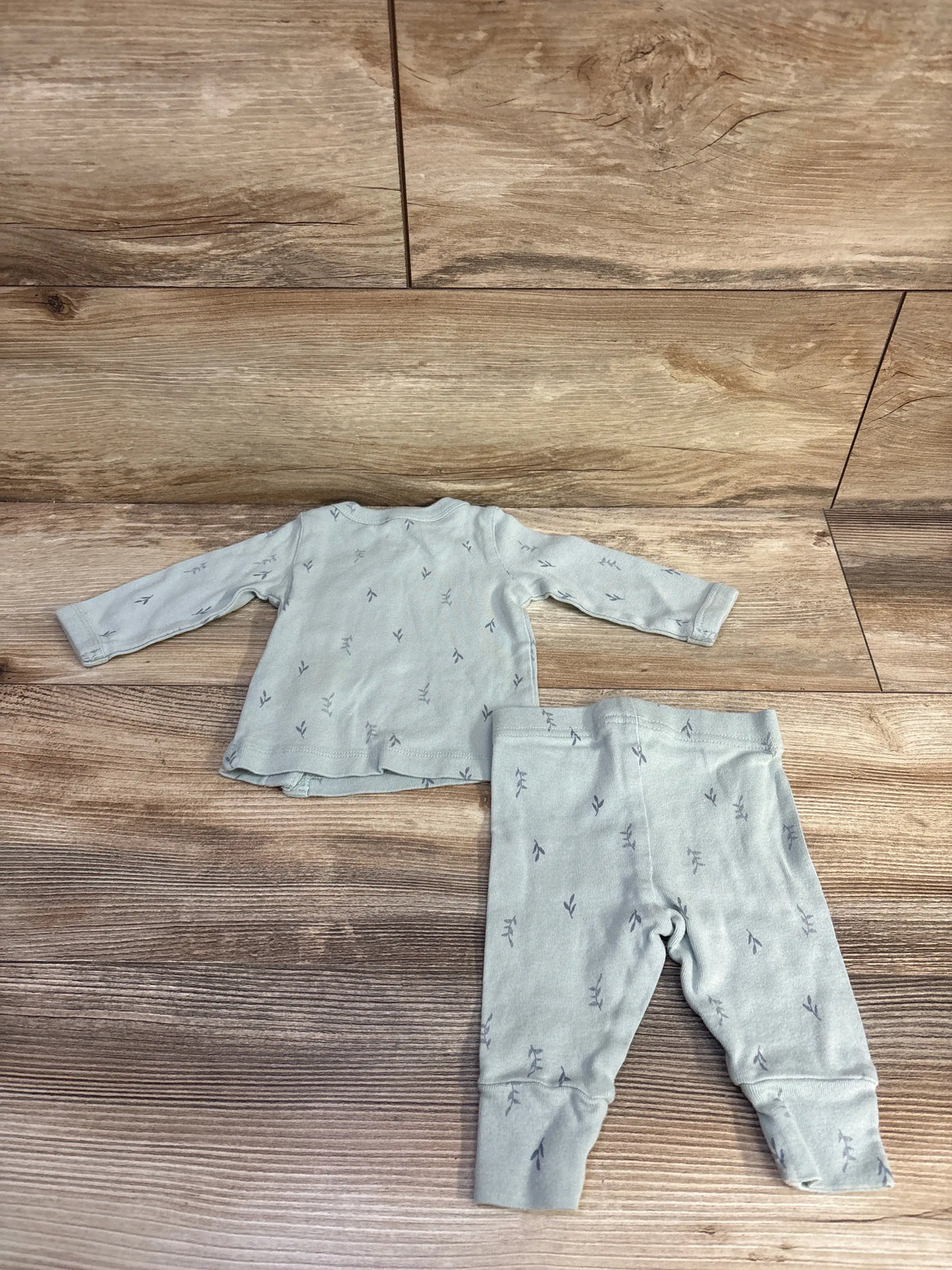 Flat lay of green Just One You two-piece kimono shirt and pants set showcasing a matching sprig pattern on wood
