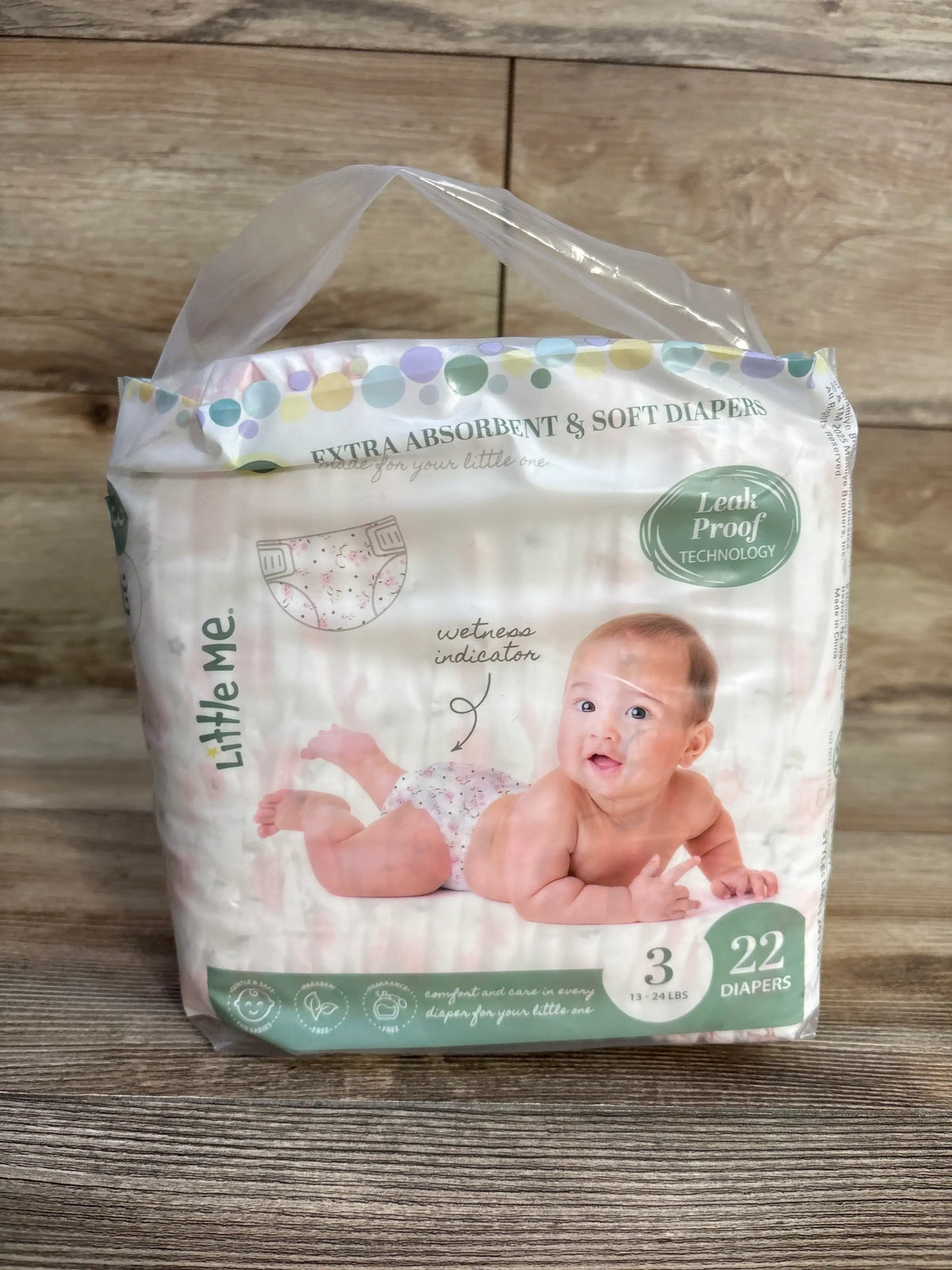 Front view of Little Me size 3 diaper pack, 22 count, baby image, wetness indicator, Leak Proof badge on wood surface